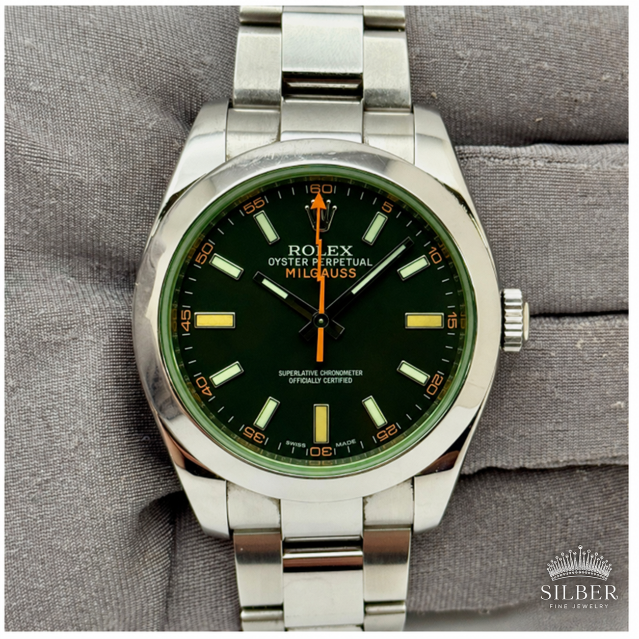 Green-dial watch on gray cushion.png