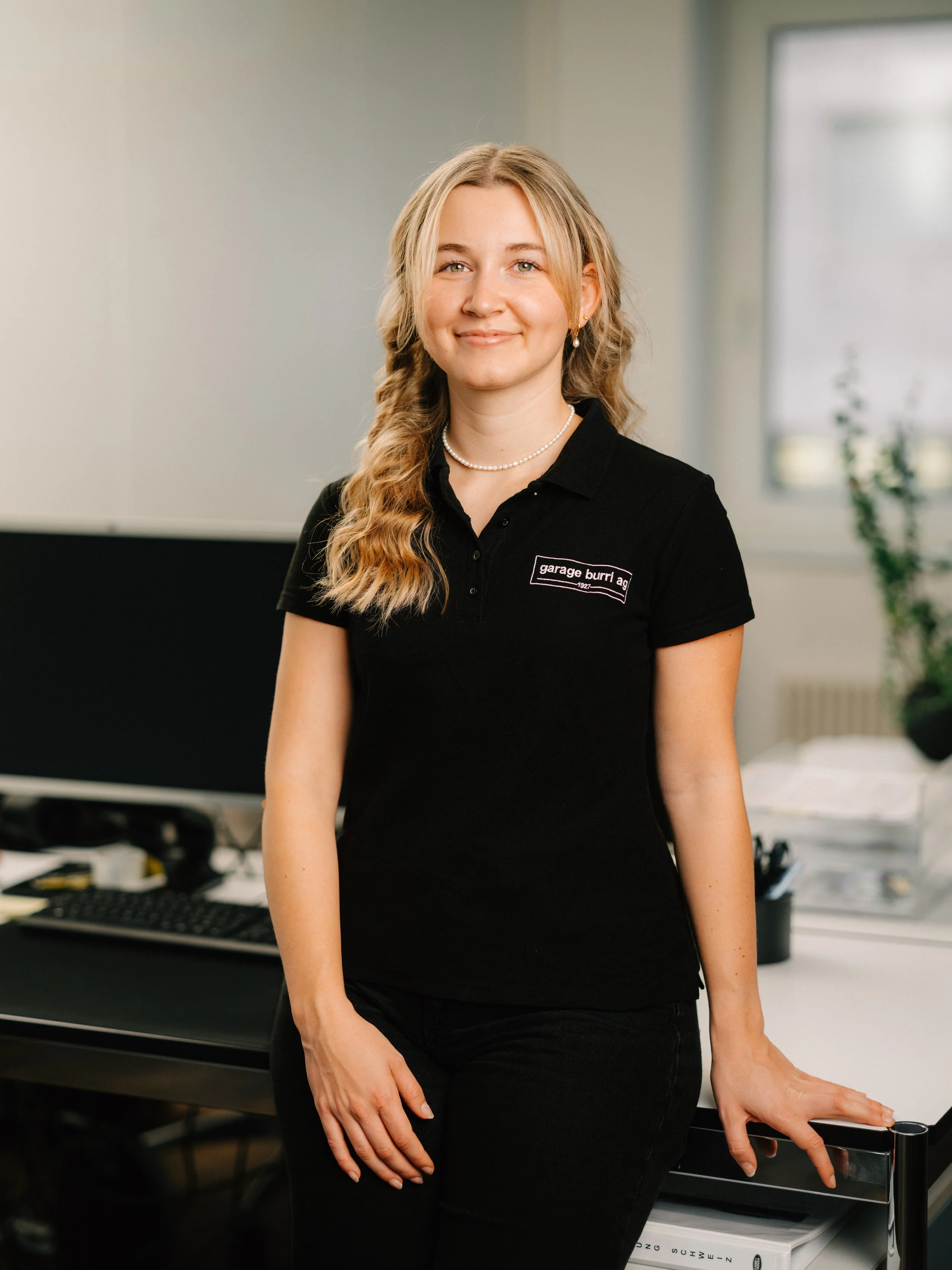 Junge Frau in weißem Polo-Shirt vor einem geometrischen Hintergrund.