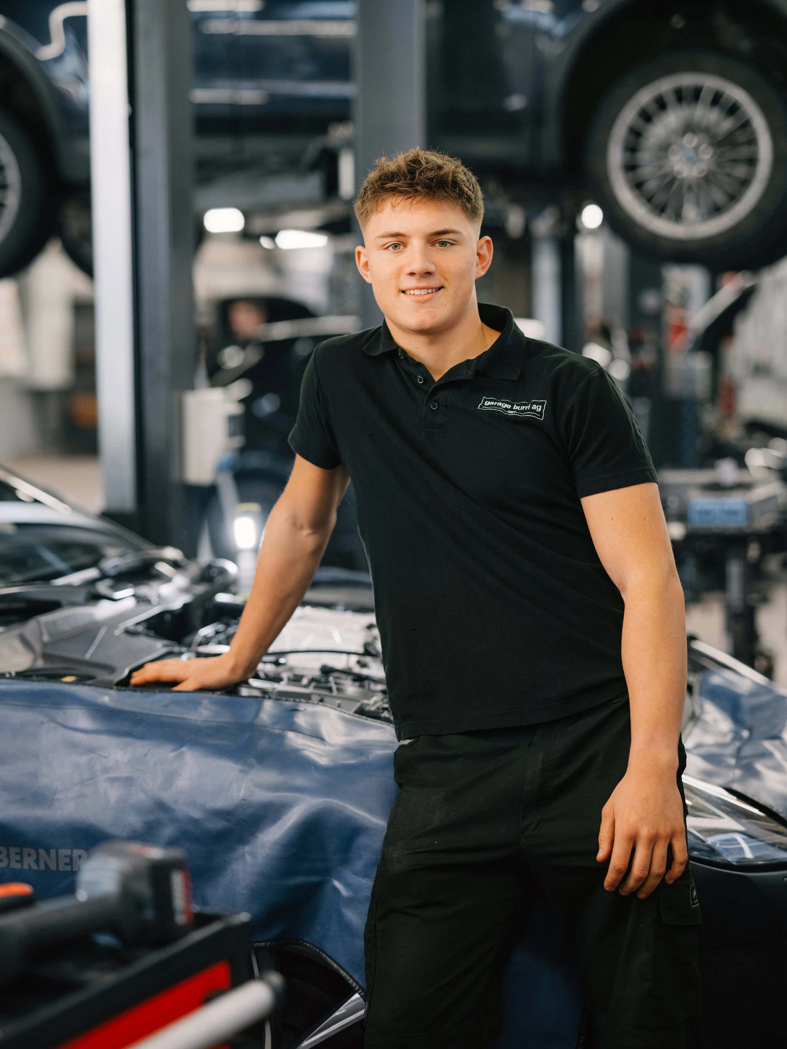 Porträt eines jungen Mannes mit hellbraunen Haaren, weißem Polo-Shirt, vor hellem Hintergrund mit geometrischem Muster.