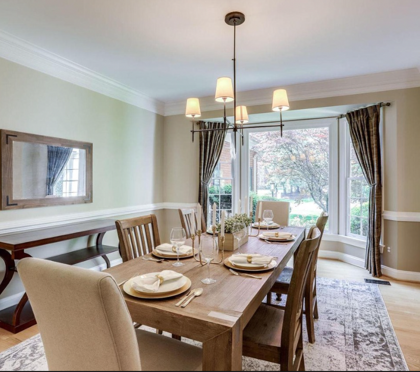 DOGWOOD FARM LN, GREAT FALLS, VA:
This elegant dining room in Dogwood features a classic wooden dining table set, complemented by a beautiful chandelier. A large window allows natural light to fill the space while offering a serene view of the backy