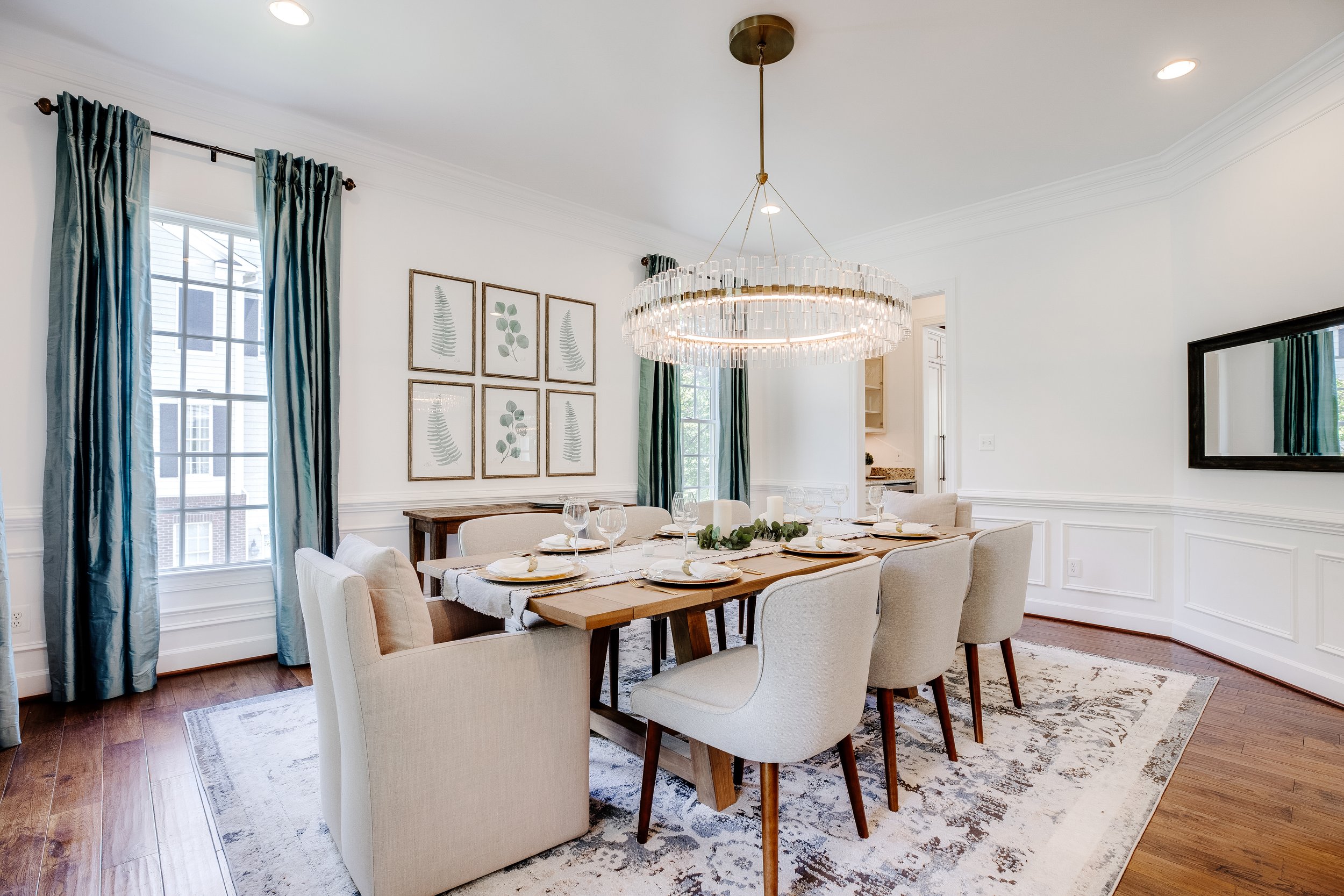 QUAKER LN, ALEXANDRIA, VA:
This charming dining room features a wooden table set with plates and glasses, creating a stylish and functional dining space. A large chandelier hangs above, adding elegance and warmth to the room. The large window, ador