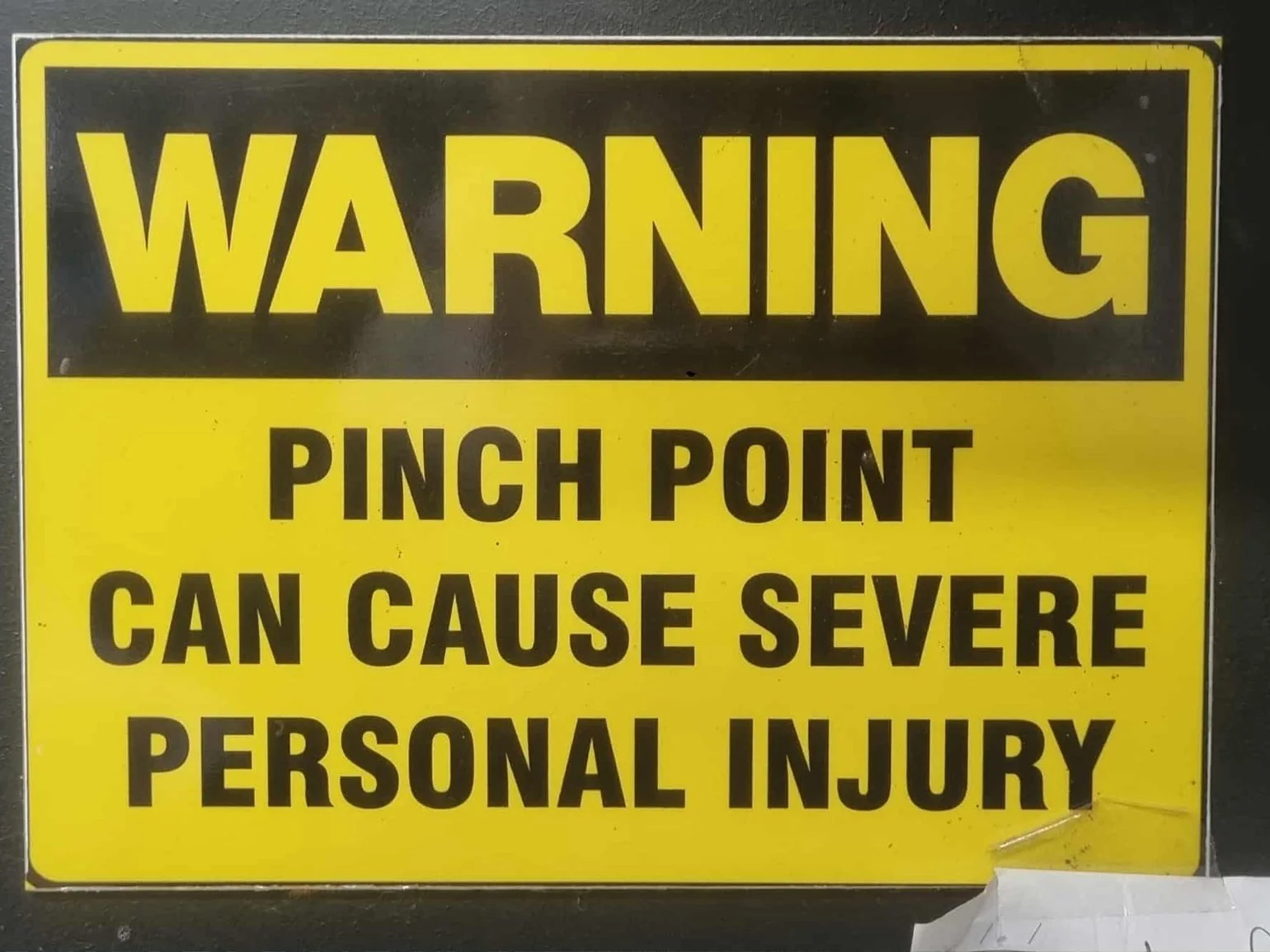 Yellow warning sign with black text stating "WARNING" and advising against a pinch point that can cause severe personal injury.