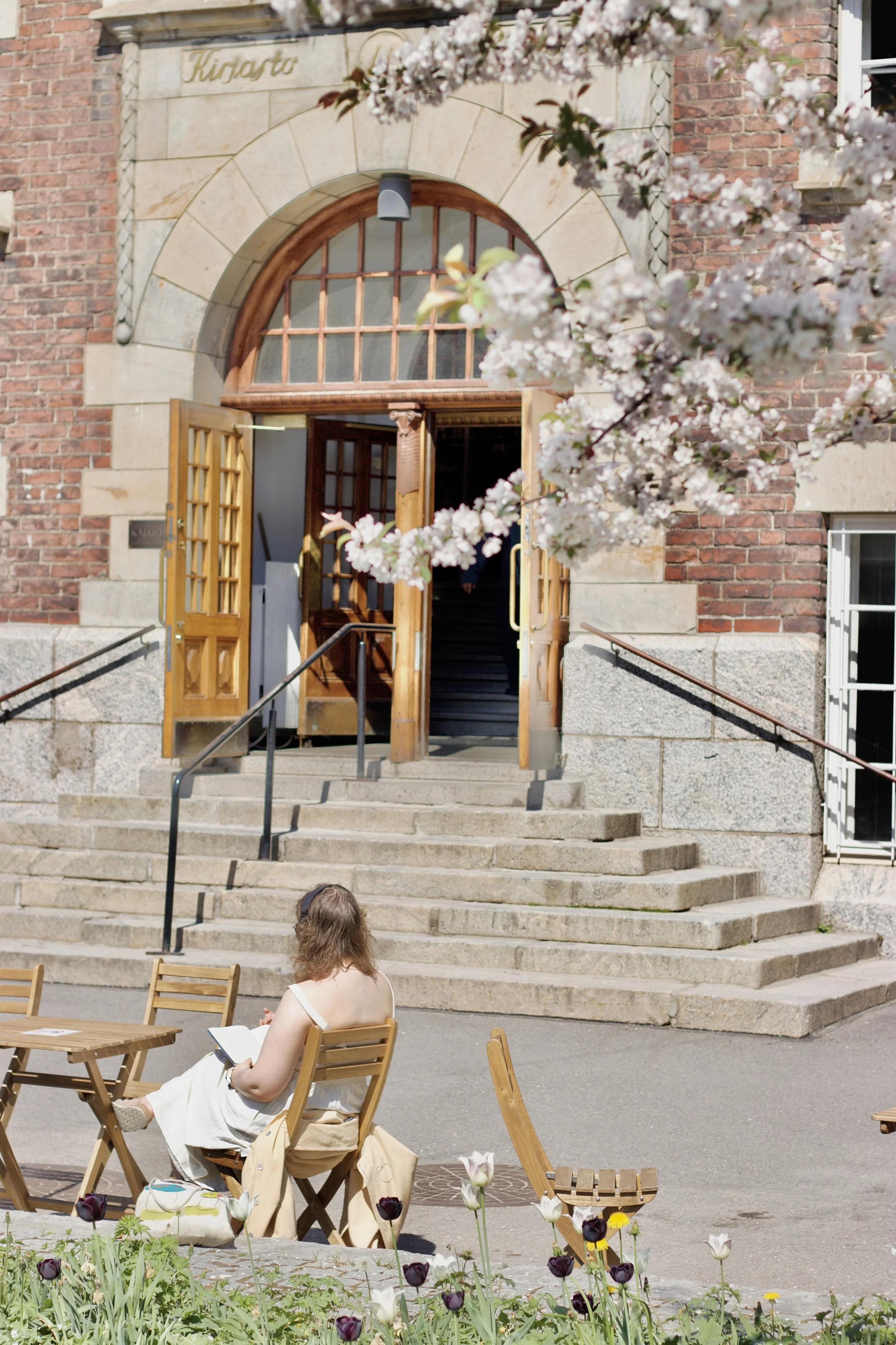  A woman sitting outside a building reading a book on a sunny day 