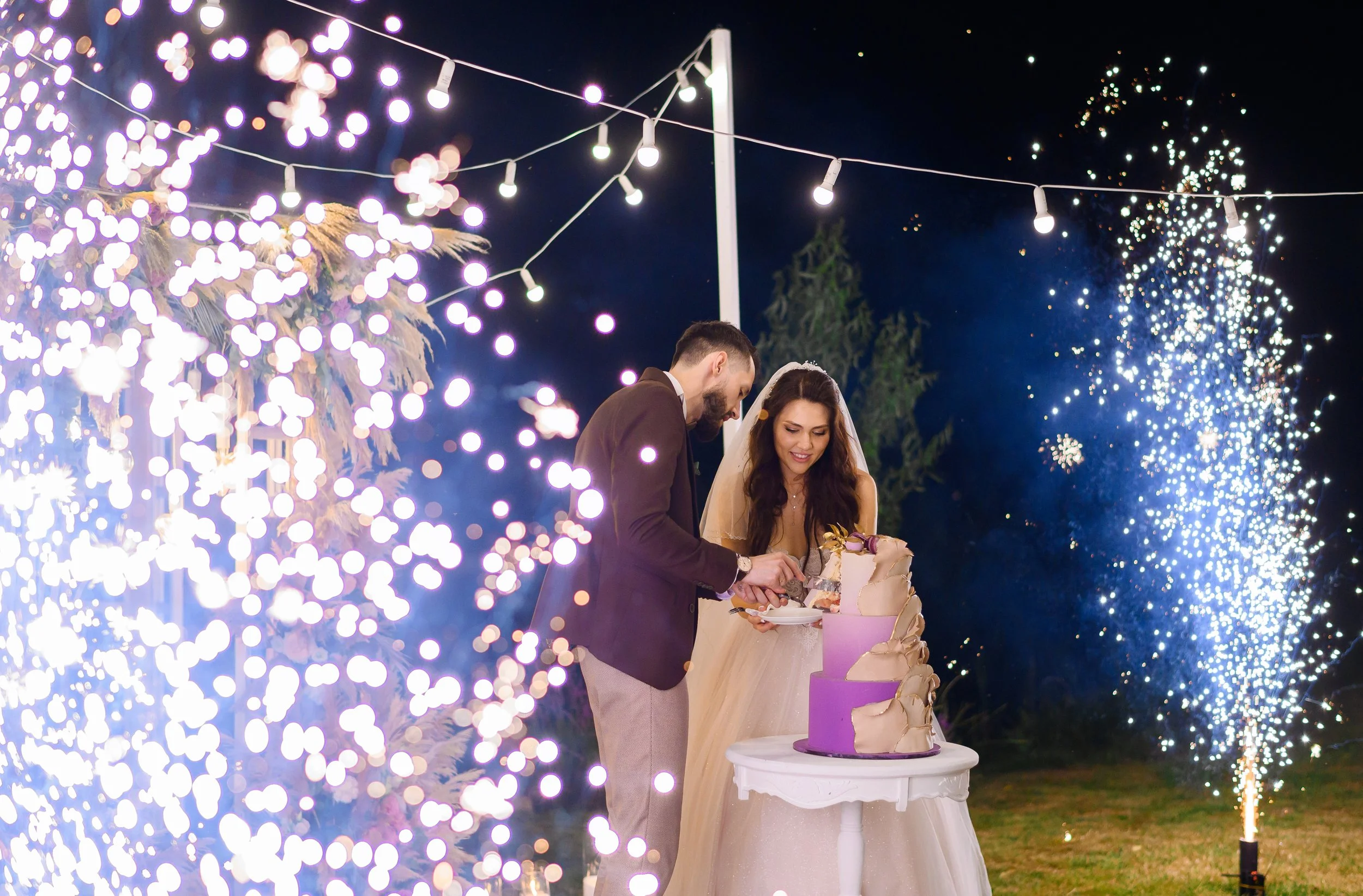 newlyweds-evening-celebration-wedding-cutting-cake-outdoors.jpg