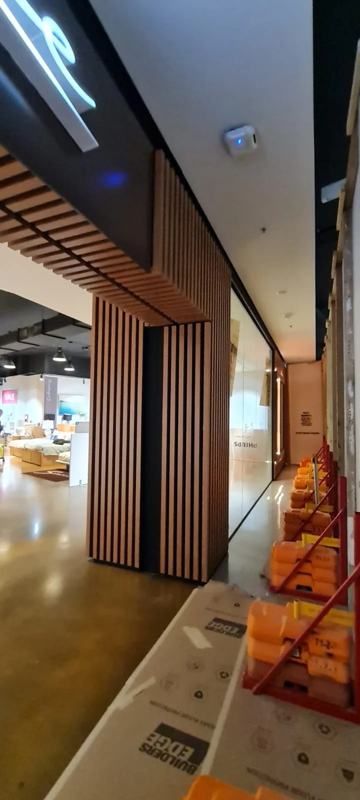 Interior view of a furniture store with wooden slat wall partitions and sale signs visible in the background.