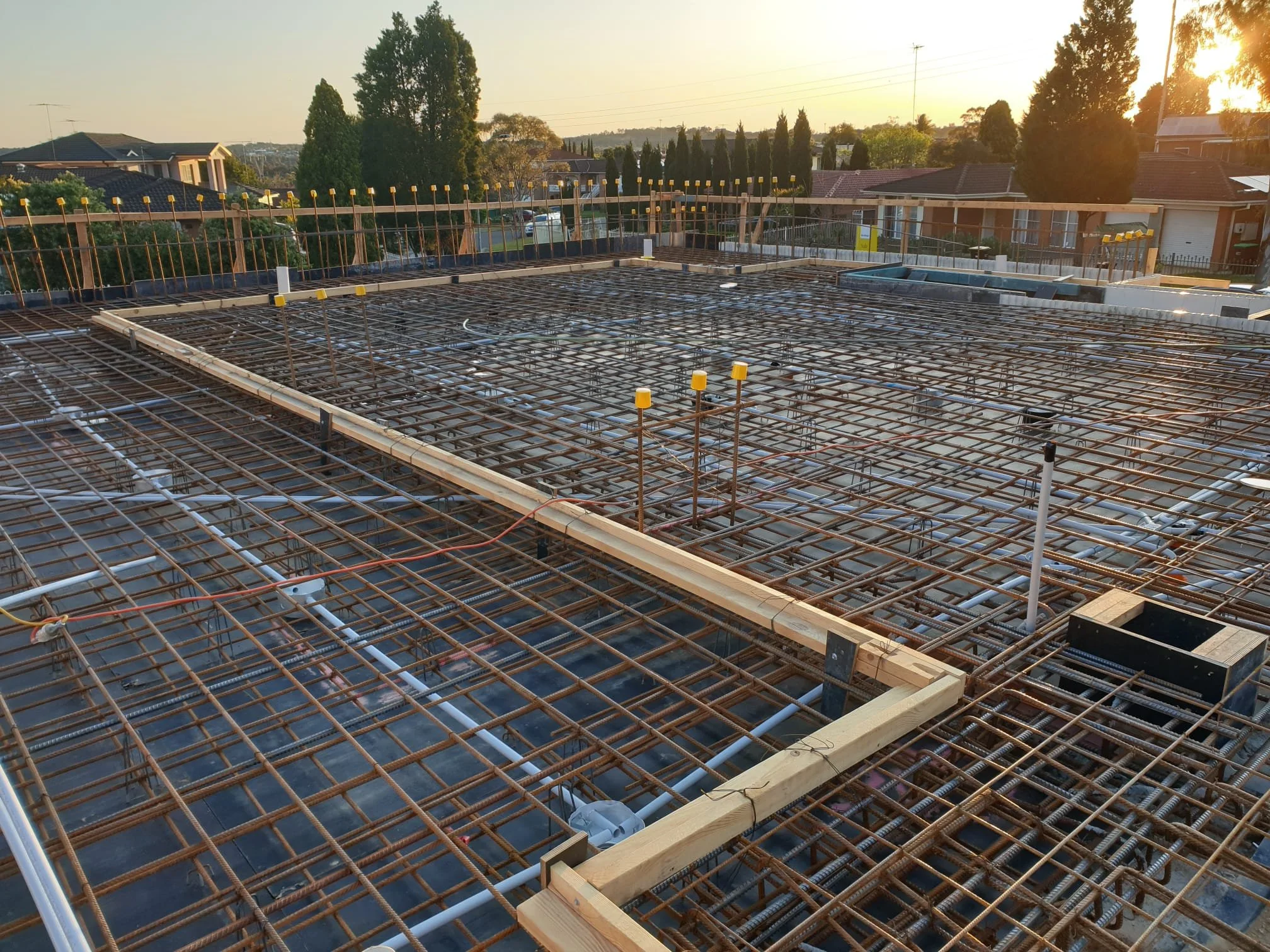 Construction site with exposed steel rebar framework for a building's foundation during sunset