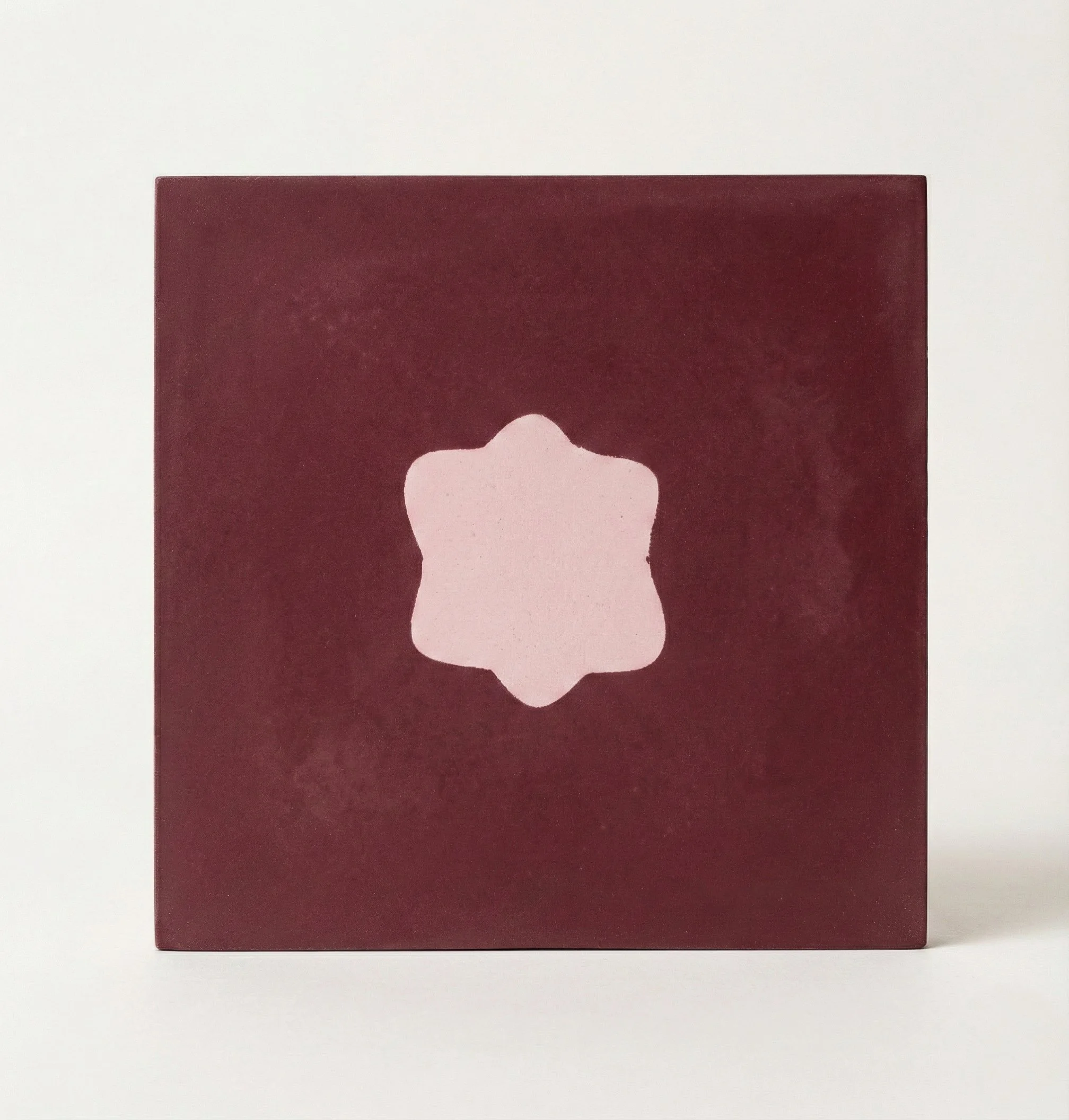 Red square box with a light pink six-petaled flower shape in the center.