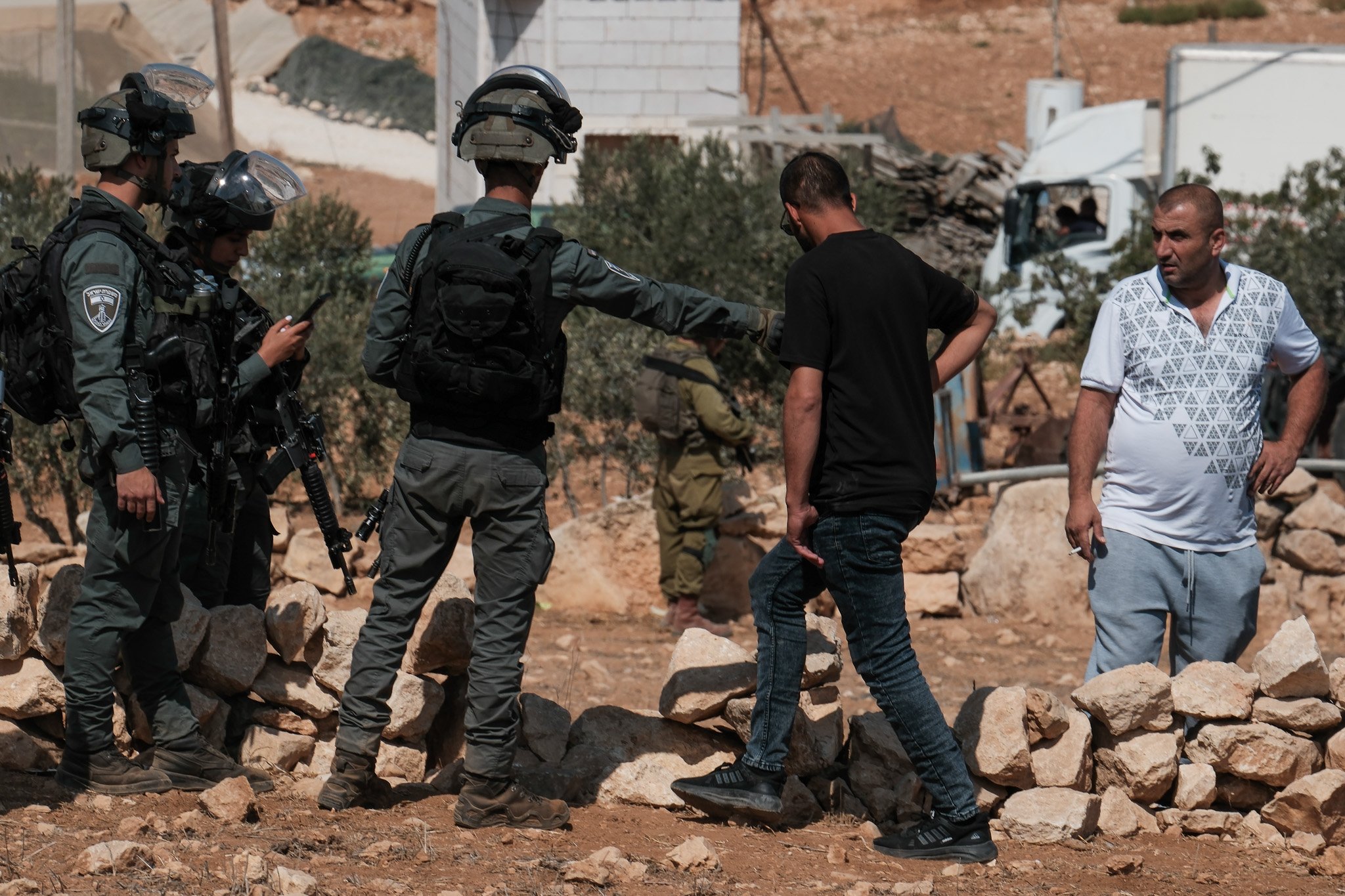 A member of the Israeli border police pushes a Palestinian man back from the site of the demolition.