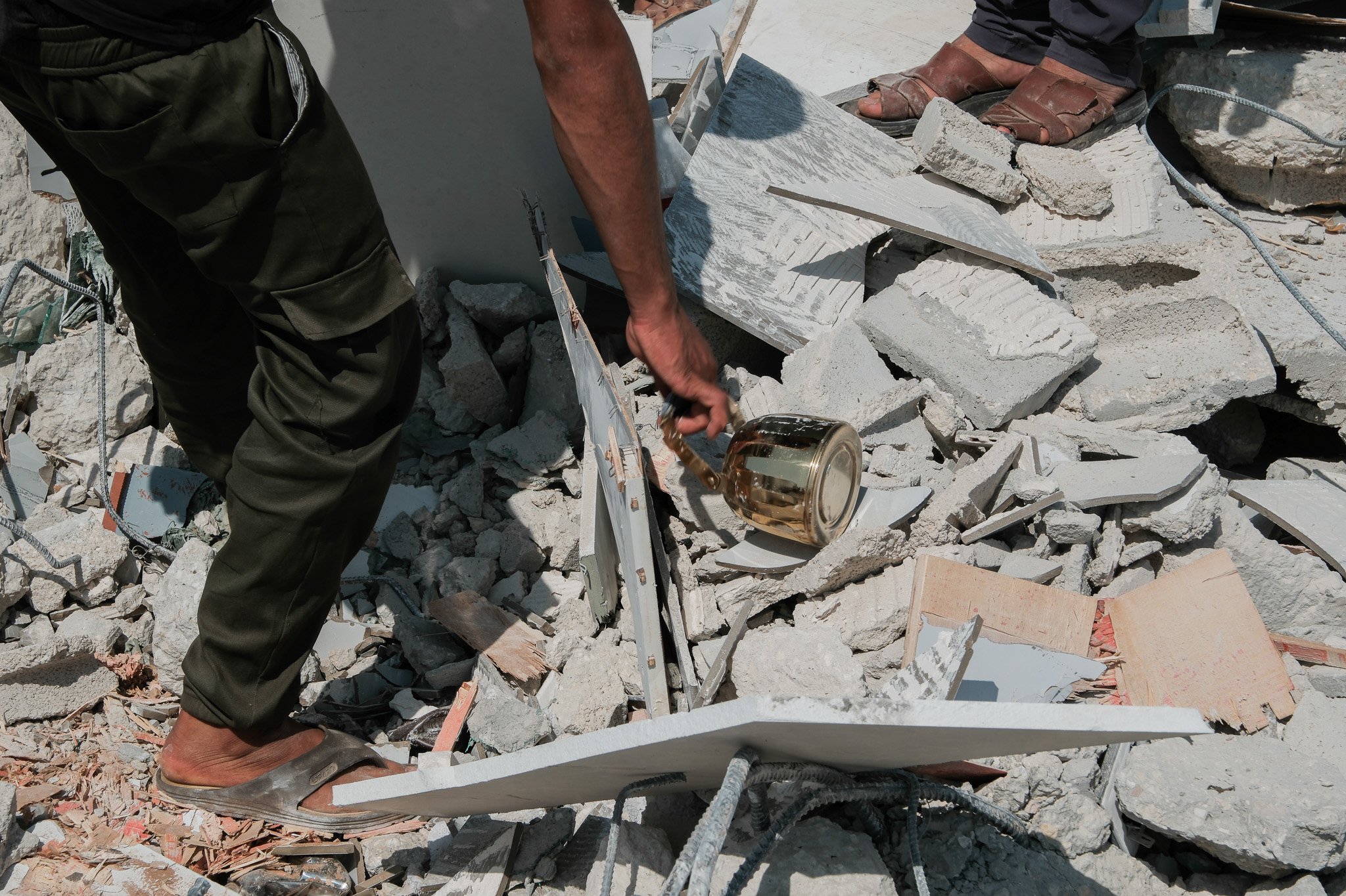 A man rescues household items left amongst the ruins of the house.