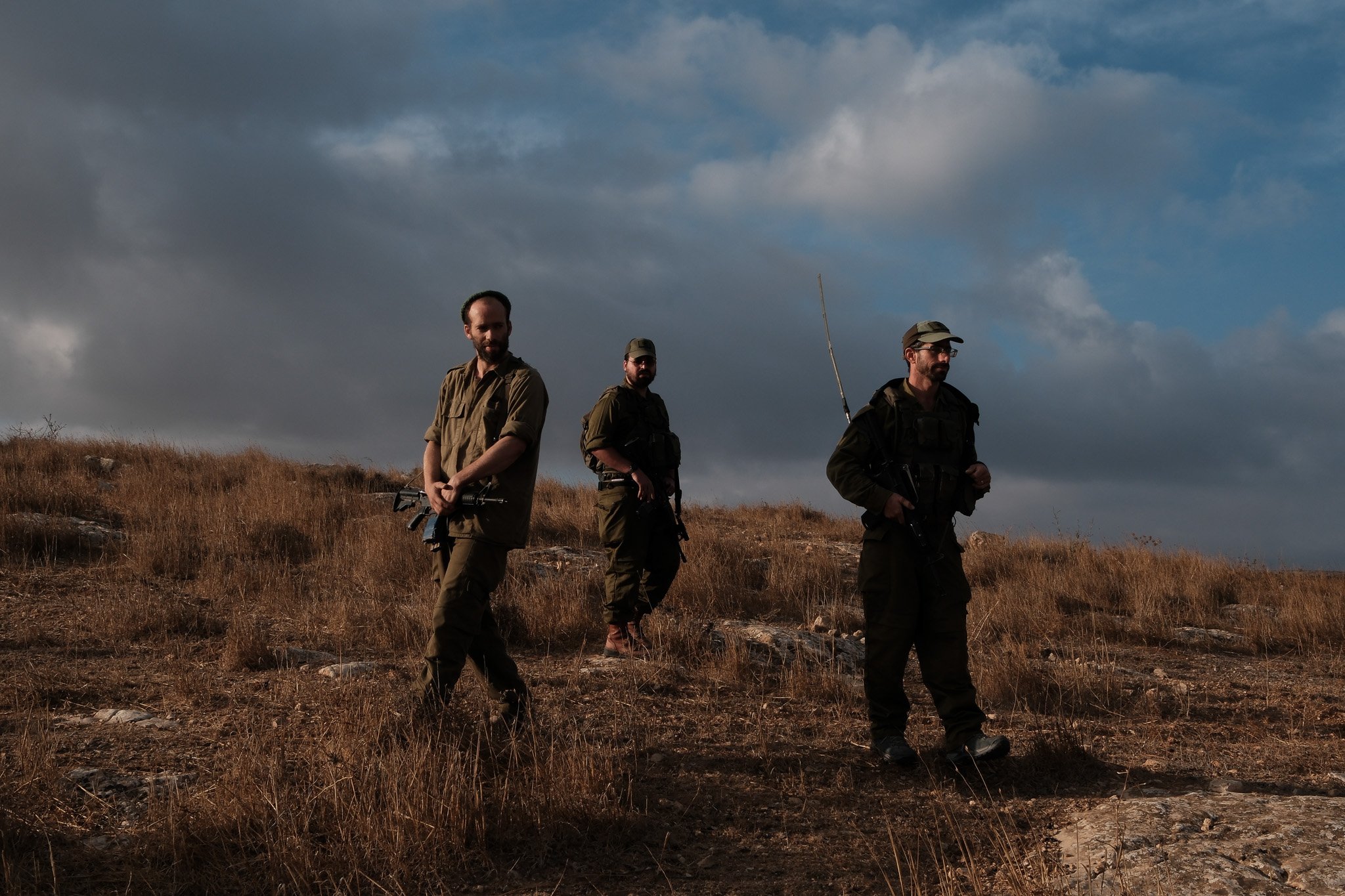 A militiaman and two Israeli soldiers patrol private Palestinian land in the early morning. Since October last year, the Israeli military has established a permanent presence on the Palestinian farm, detaining the landowners whilst settlers trespass