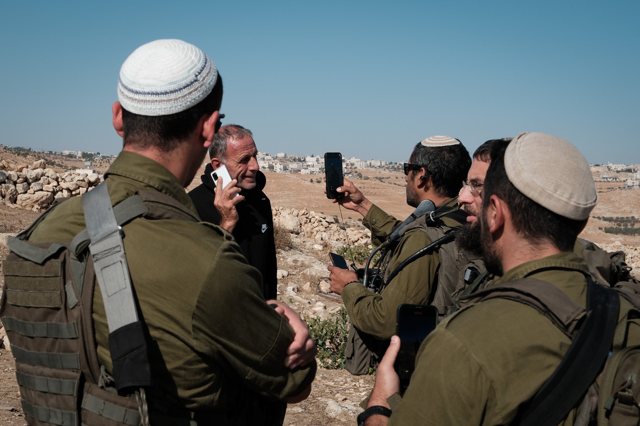 Hafez has his photo taken by the Israeli military whilst on the phone to the Israeli police. Everyday, Palestinians are photographed and have the ID documents checked, often by Israeli settlers and police who already know them by name. 