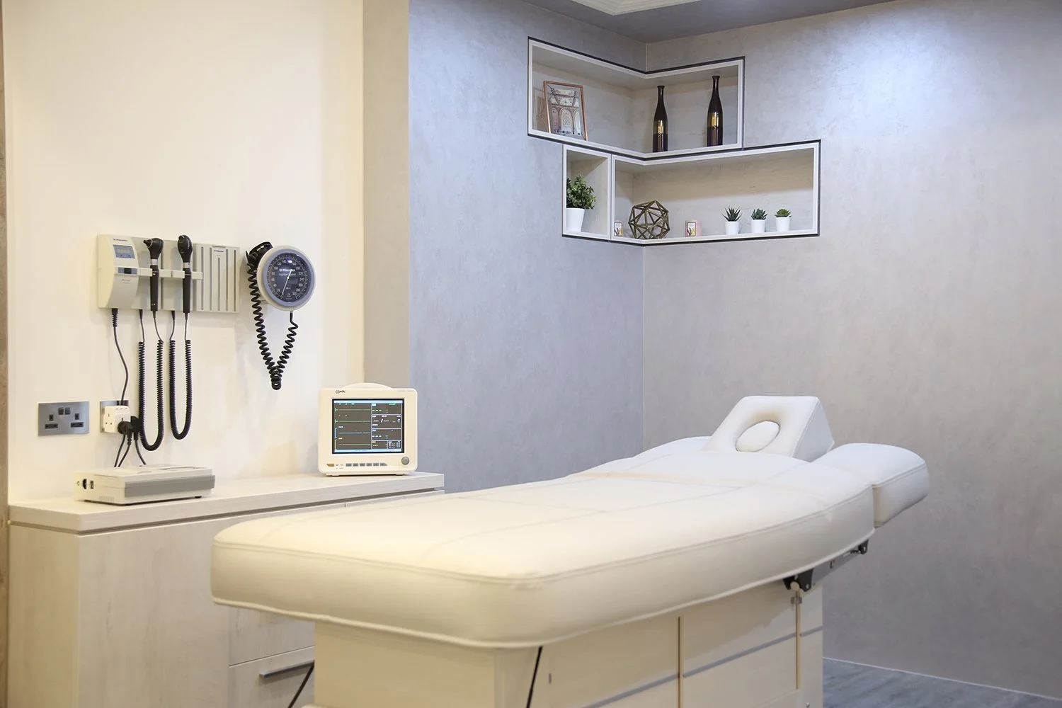 Serene treatment rooms with a calming color palette and thoughtful design create a tranquil escape. Varying ceiling levels subtly separate the treatment area from the doctor's consultation space.