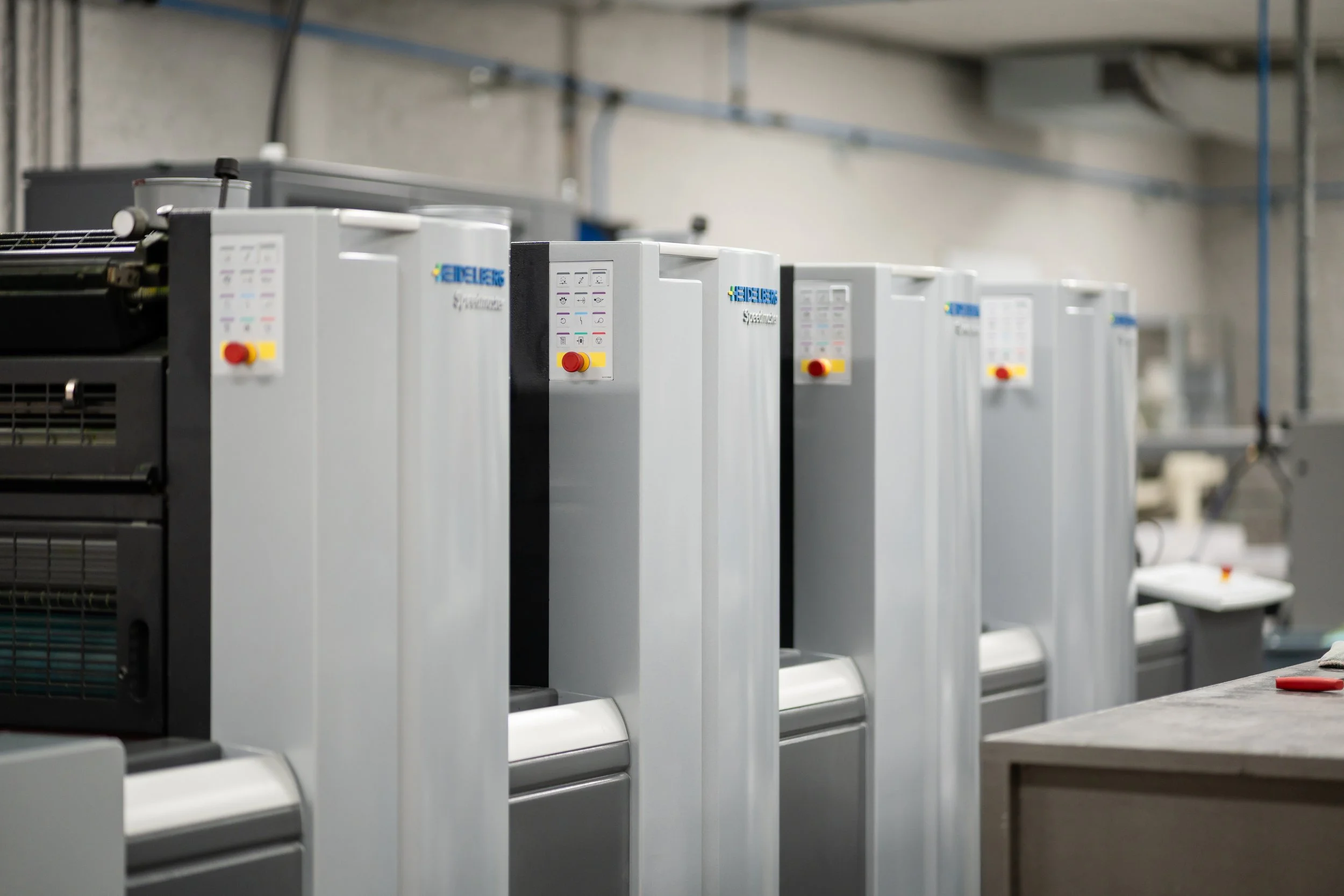 Lignes de machines industrielles dans une usine avec un mur en béton et des tuyaux au plafond