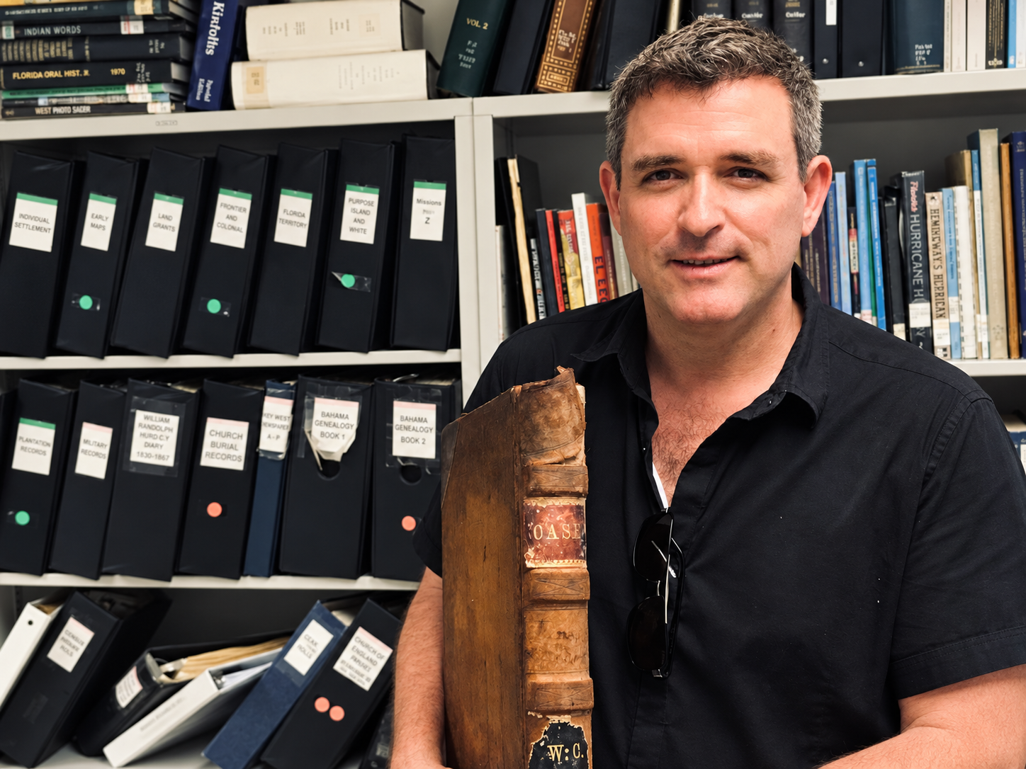 David Sloan holding an antique book while researching Key West history in an archive