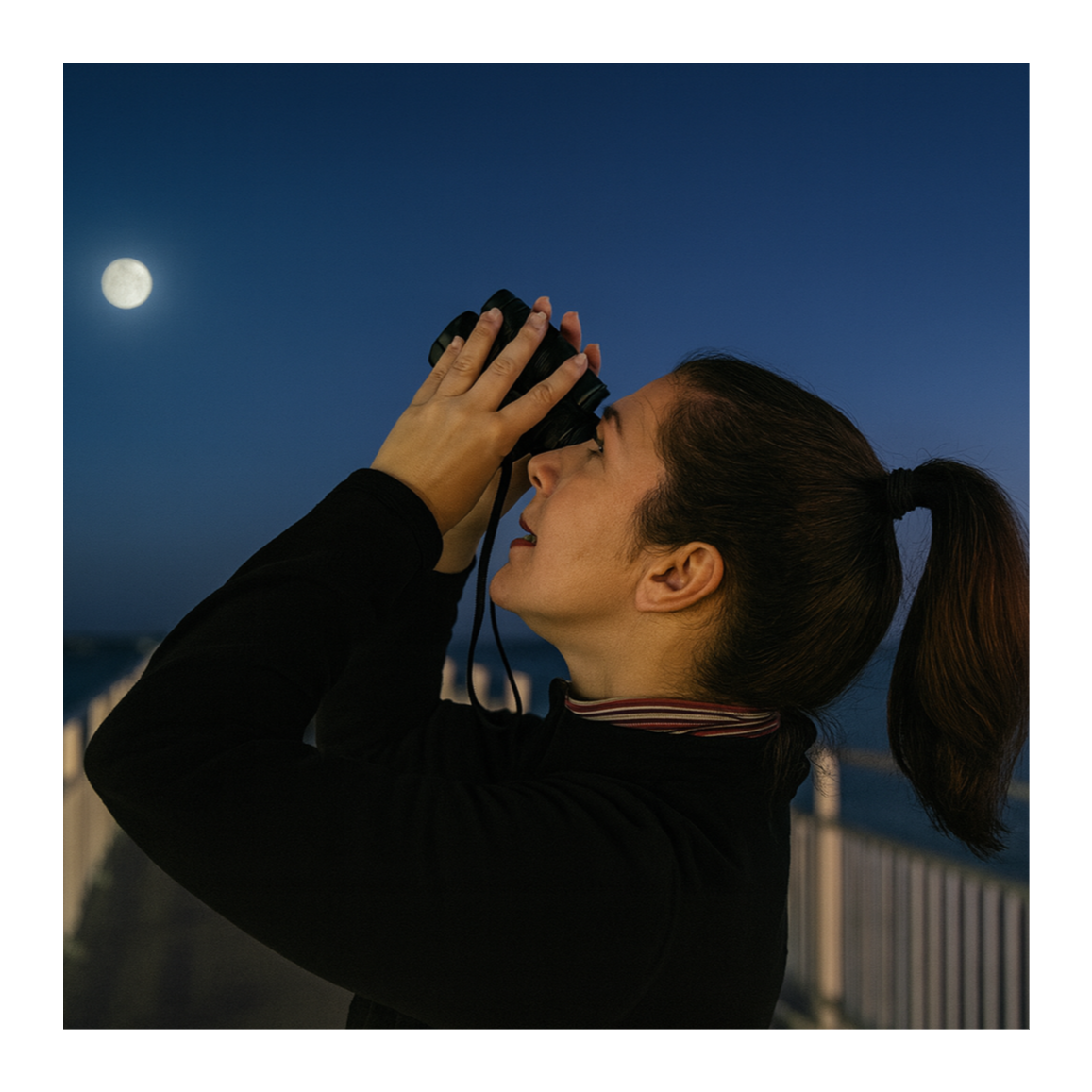 Woman looking through binoculars at the night sky with a full moon visible.
