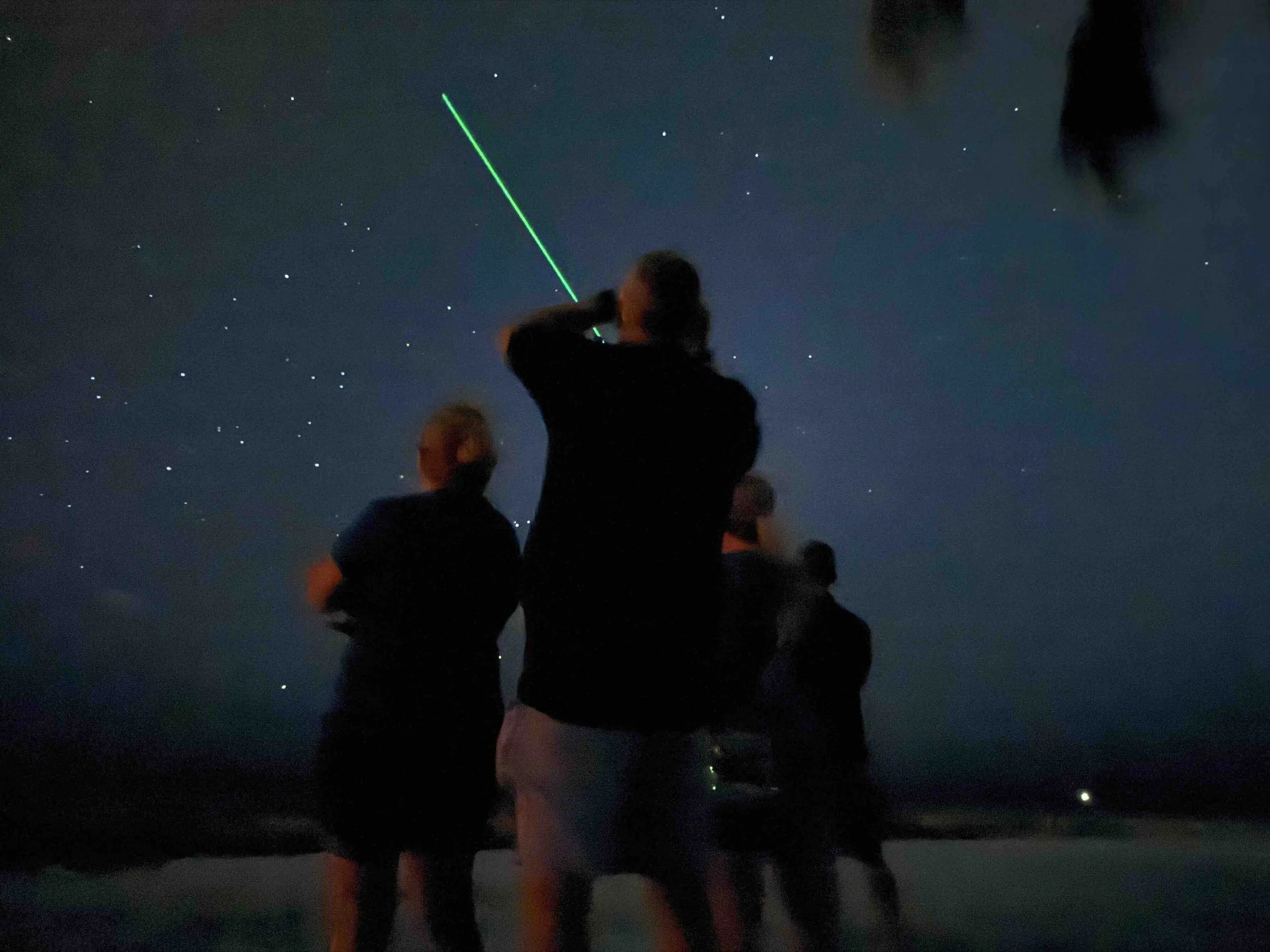 Guests on the Key West UFO Tour using a green laser pointer to observe the night sky along the Key West waterfront.