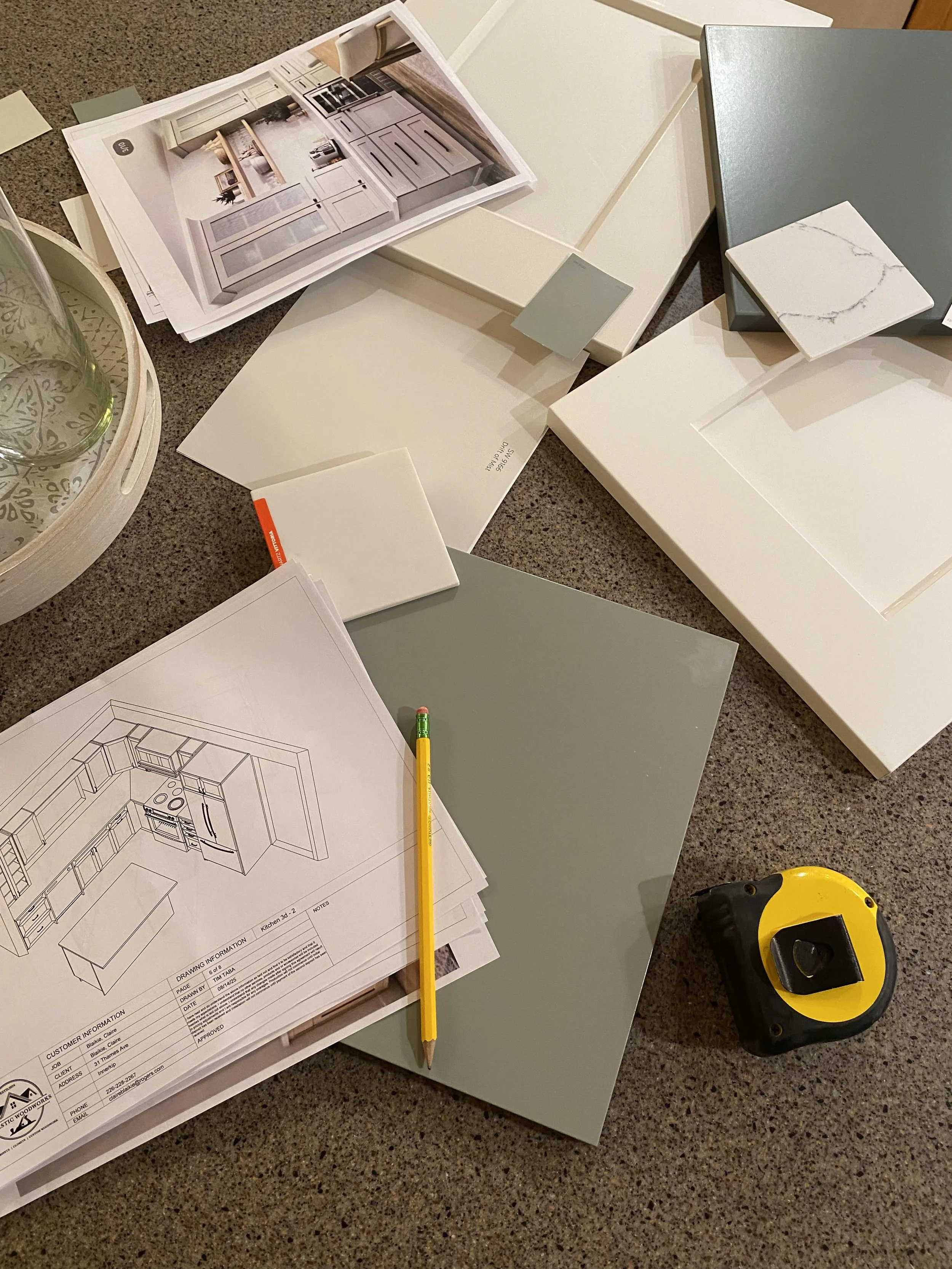 Interior design mood board with color samples, fabric and material swatches, a pencil, and a kitchen layout plan on a textured surface.