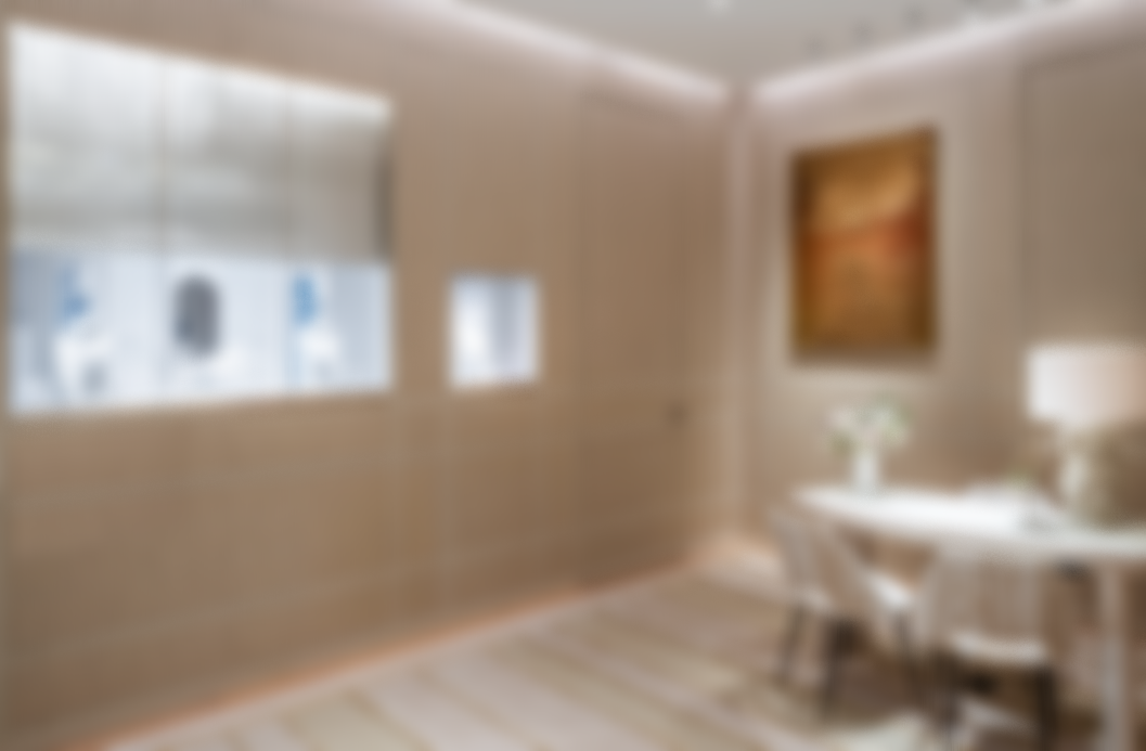 Blurry image of a well-lit dining room with a table, chairs, a painting on the wall, and a vase with flowers.