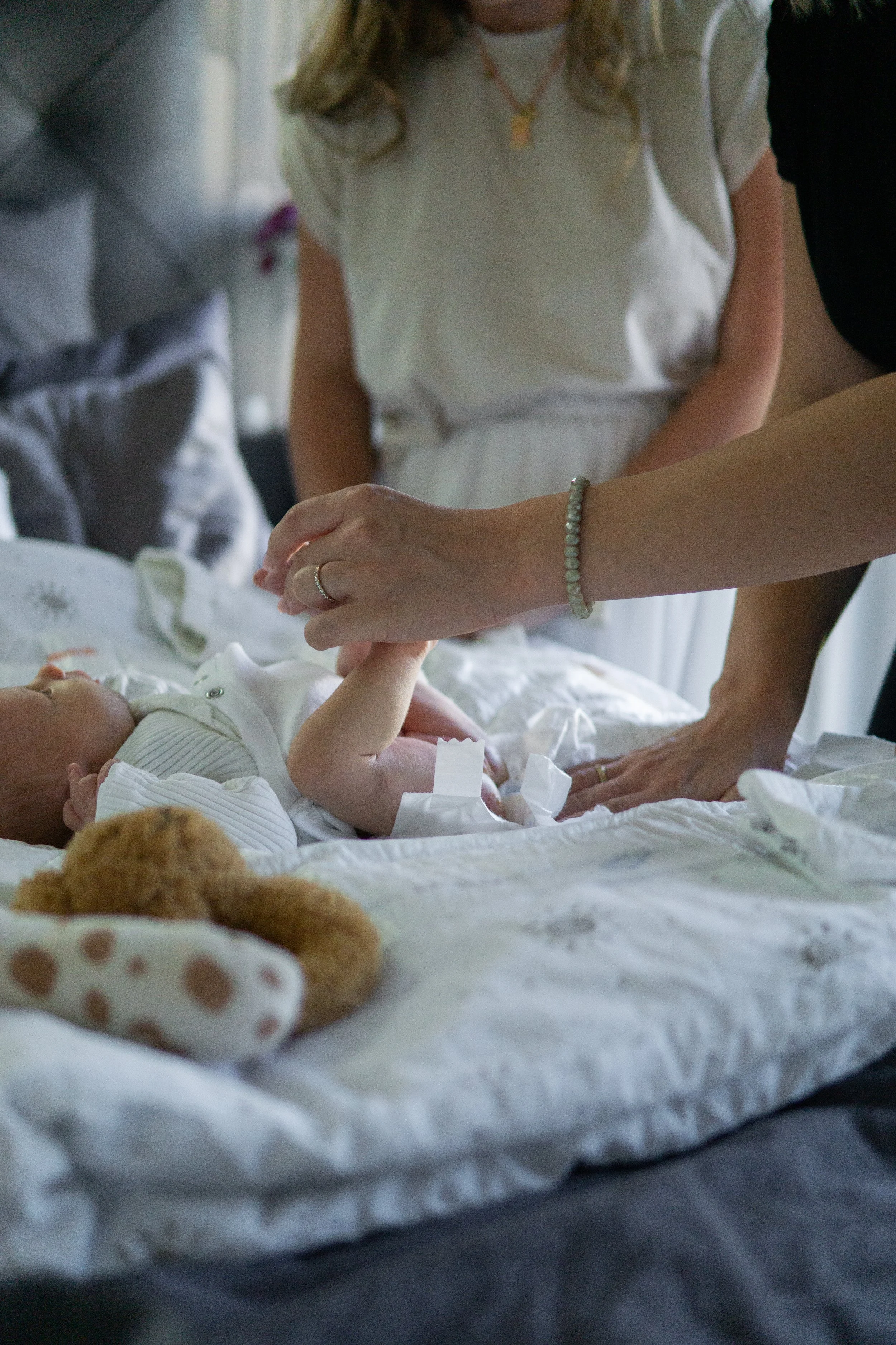 Eine Mutter wickelt ihr Baby auf einem Wickeltisch, während Hebamme Sina daneben steht und sie unterstützt.