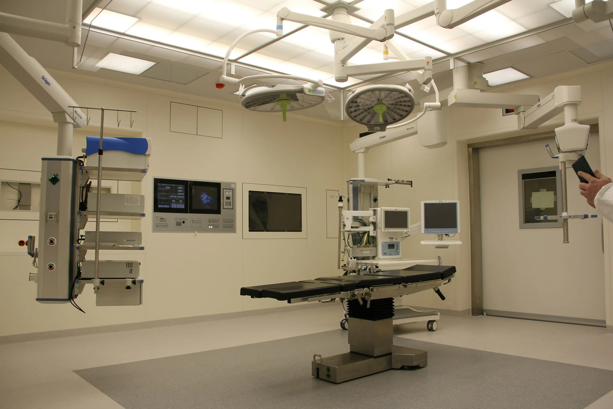 Modern operating room with surgical table, medical monitors, and overhead lights in a hospital.