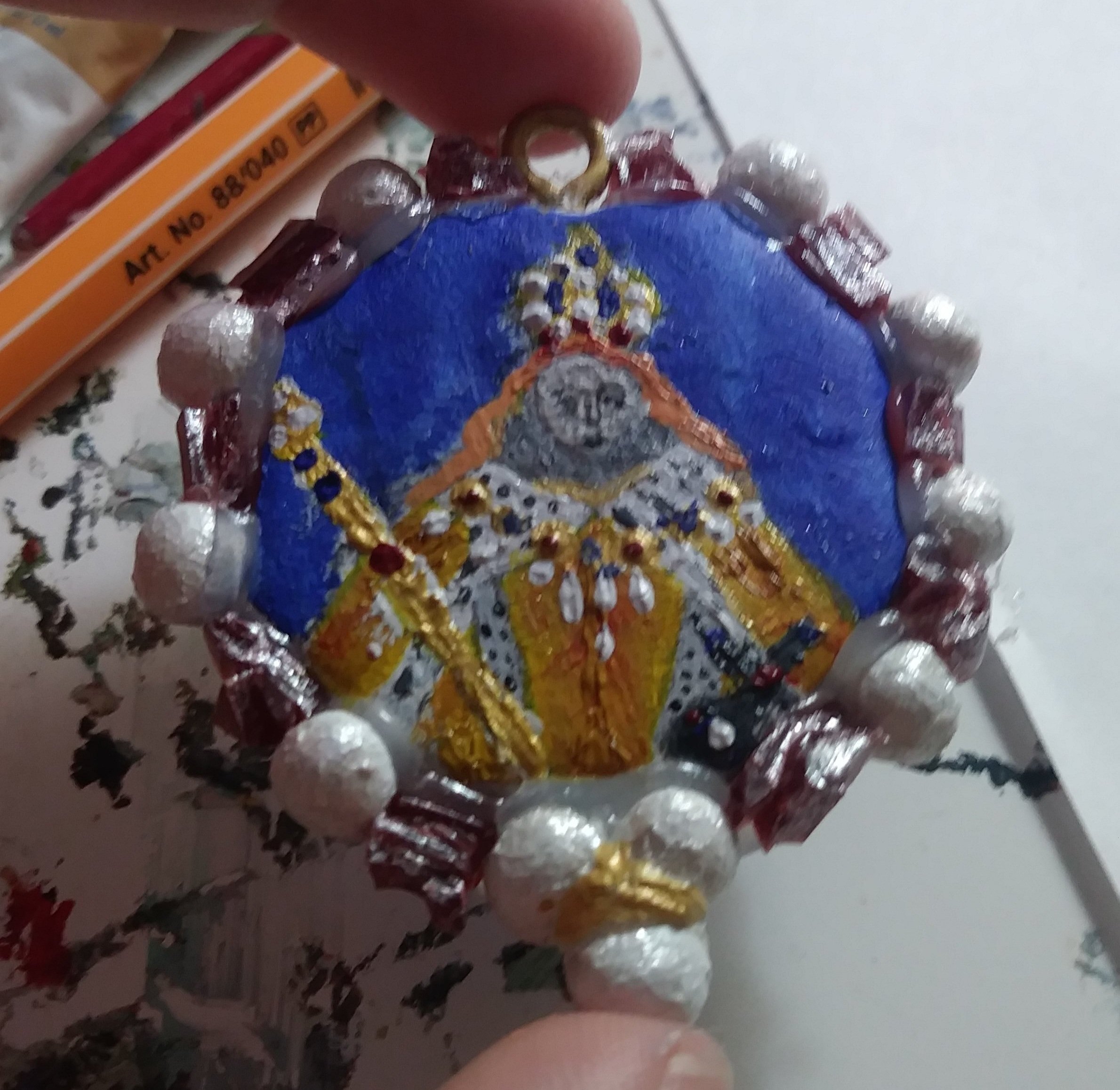 2" medallion showing a copy of the corination portrait of Elizabeth 1, circled by handmade faux pearls and diamonds. Oven bake clay with acrylic.