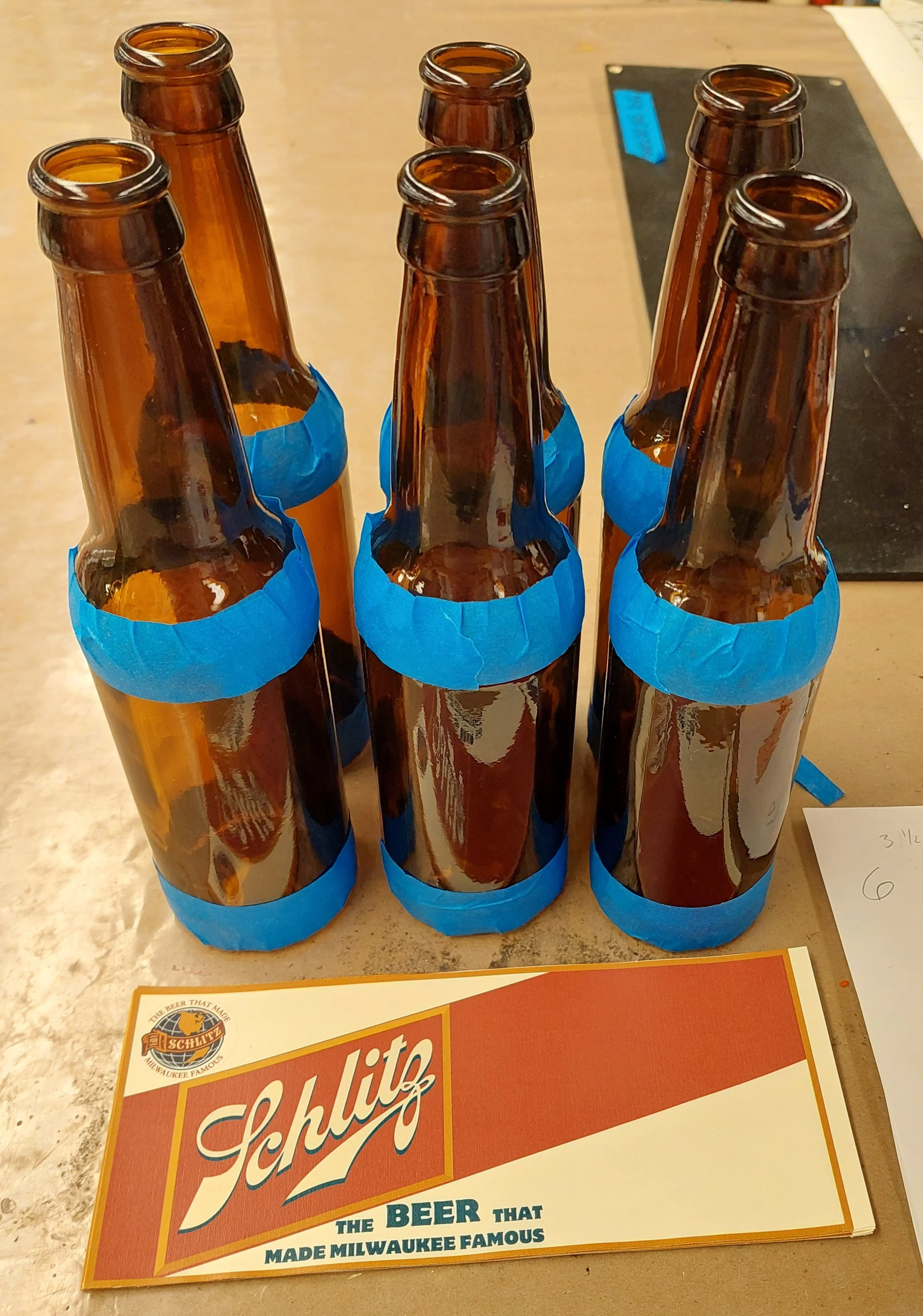 We wanted to avoid pure white on the set so the labels were printed on cream paper. Scuffed the bottles using tape as a guide. Used spray adhesive for this version.