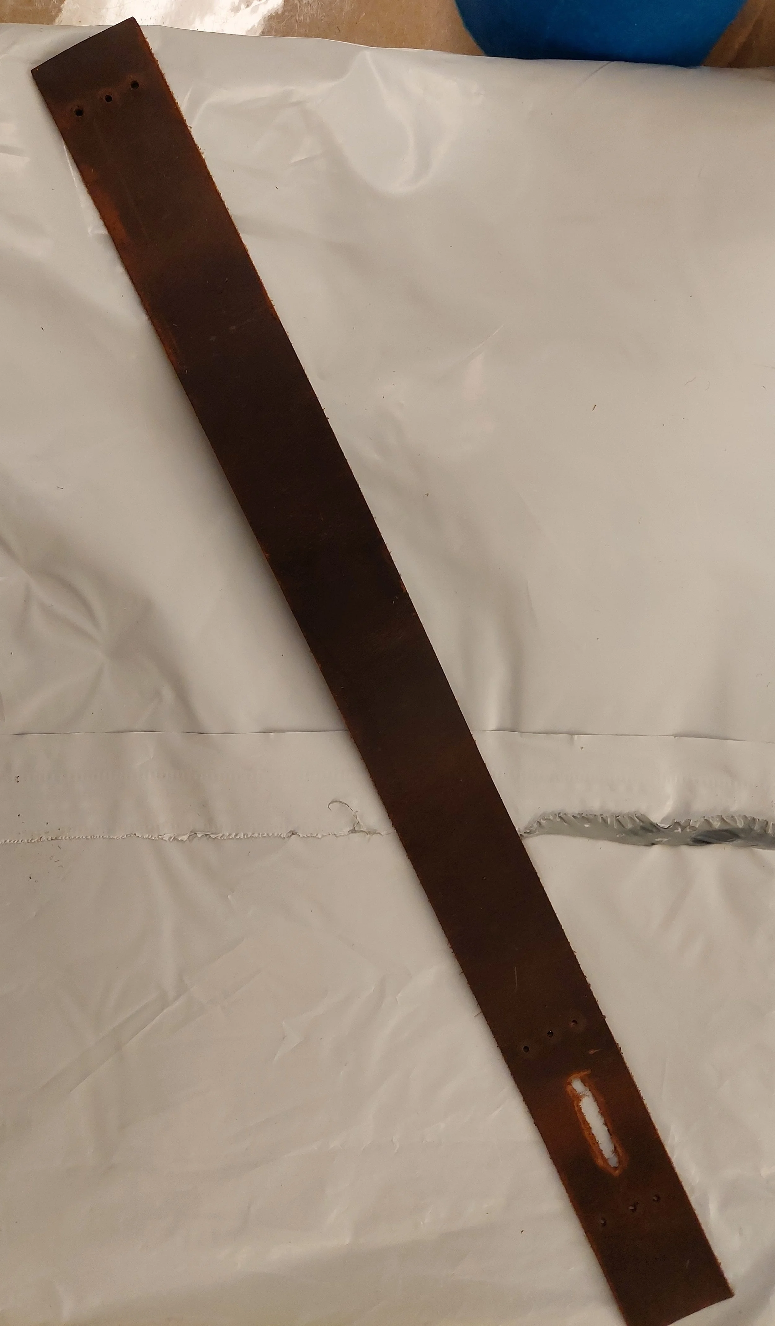 Light leatherworking to make a neck strap for a wooden crate.