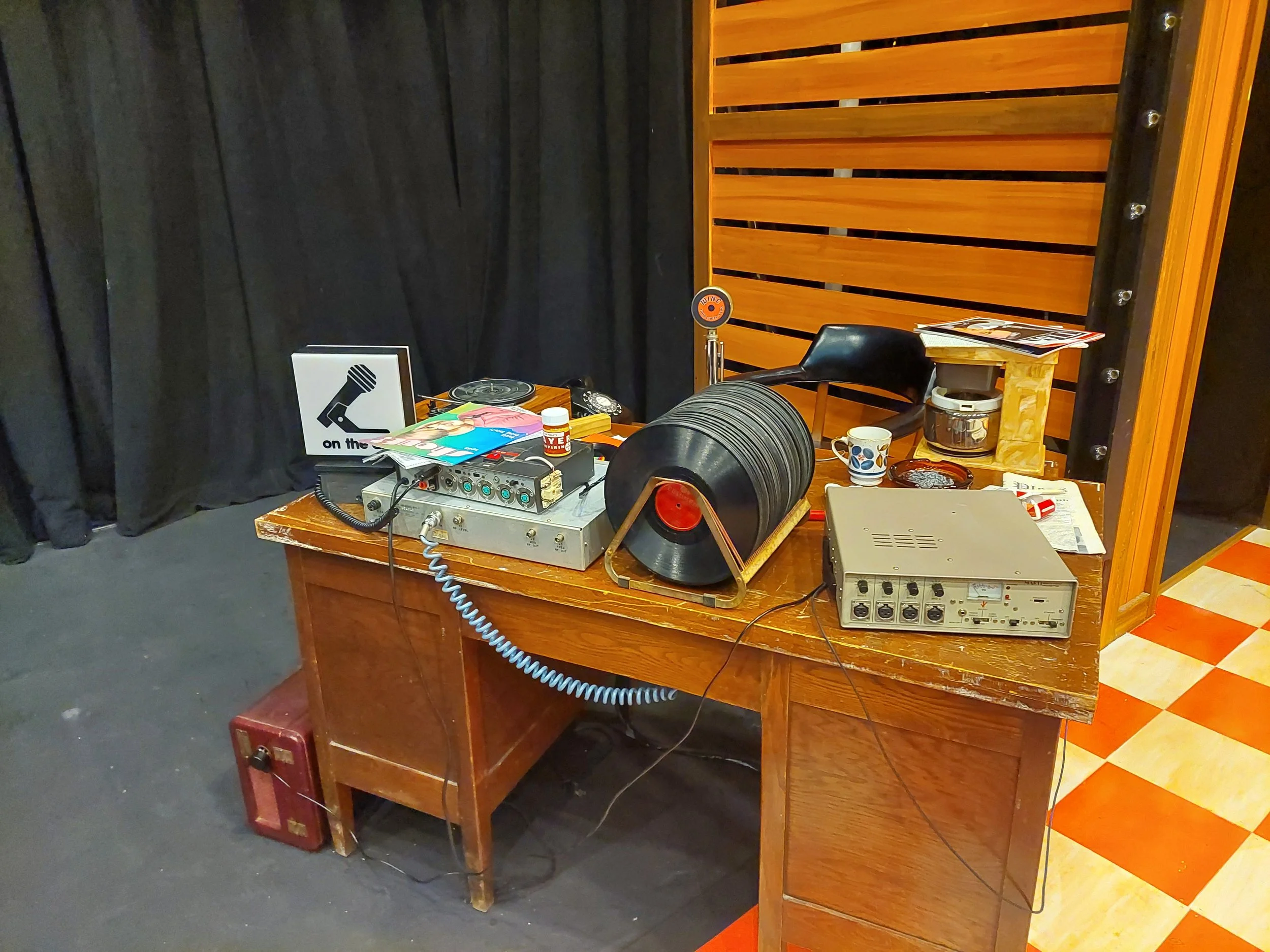 Final desk dressing onstage. Collaborated with lighting to make an old "On Air" sign functional with a small button on the back. Painted the coffee maker to avoid the stark white.