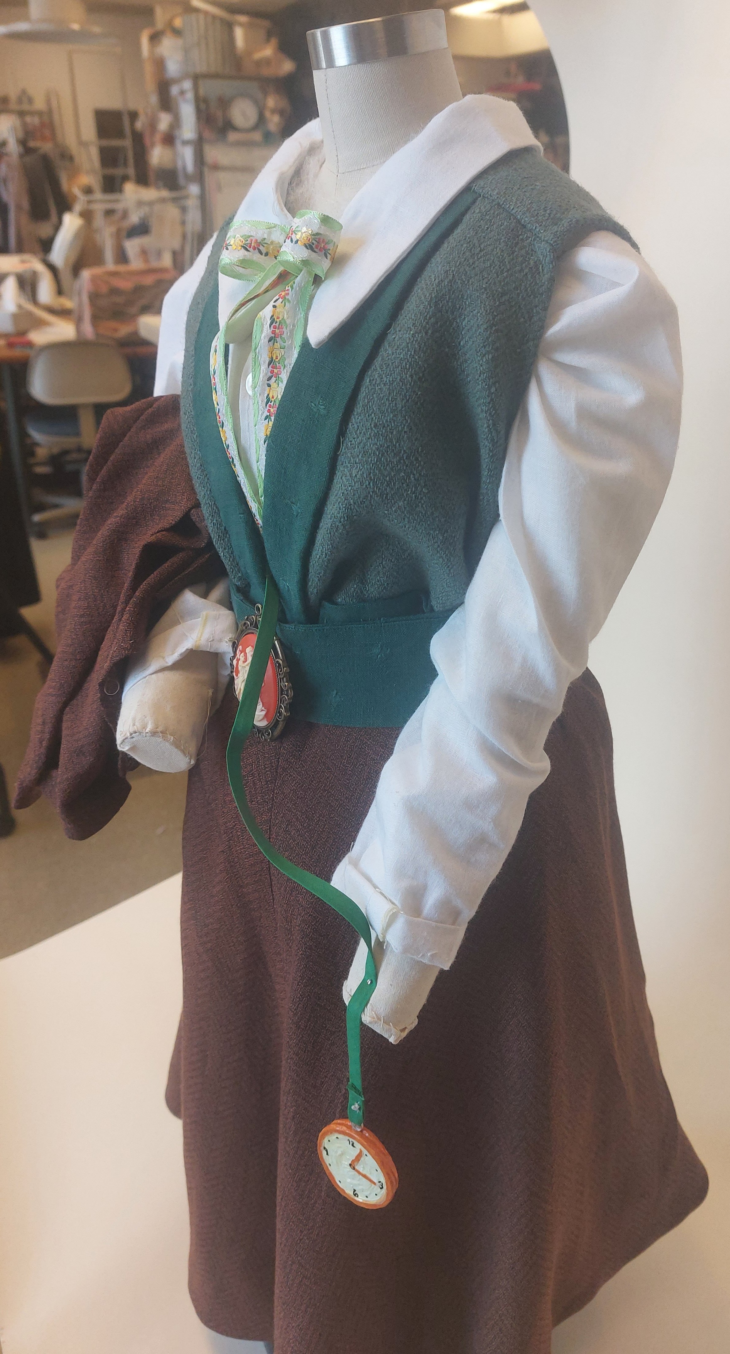 Features chemise, bum roll, skirt, shirt, waistcoat, ribbon tie, belt, jacket, and clay pocket watch.