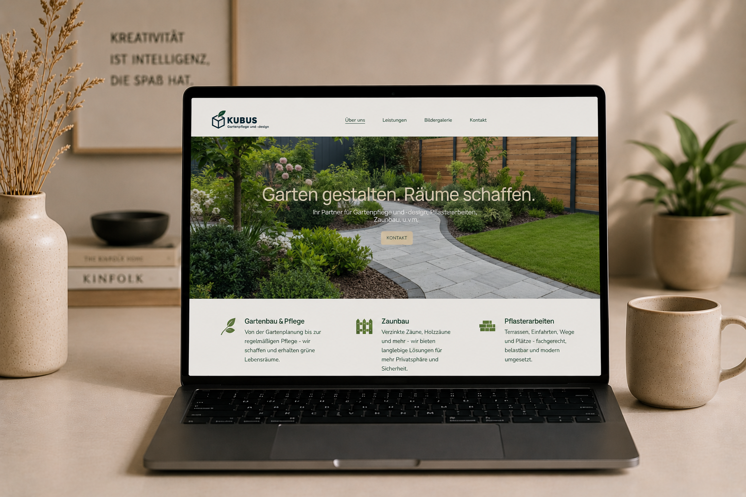 Laptop zeigt die Webseite eines Gartenbauunternehmens namens Kubus, mit Gartenweg, Pflanzen und Text über Gartenplanung und Pflege, flankiert von Töpfen und Büchern auf einem Tisch.
