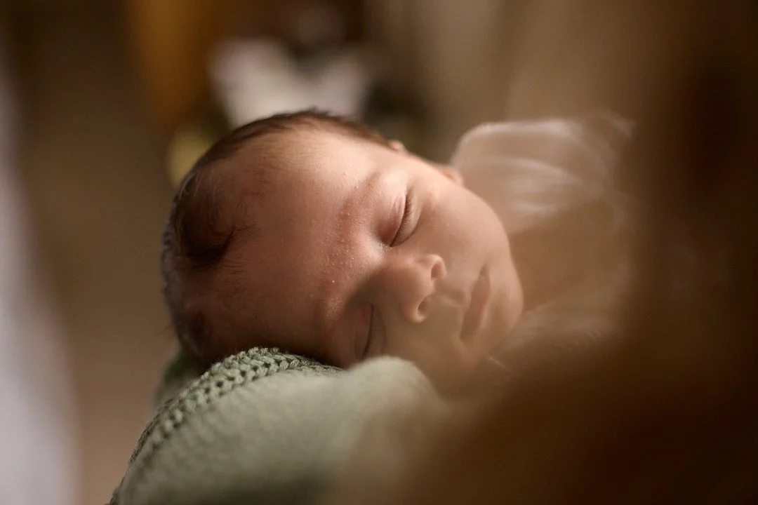 Close-up of a sleeping newborn baby resting on a knitted blanket