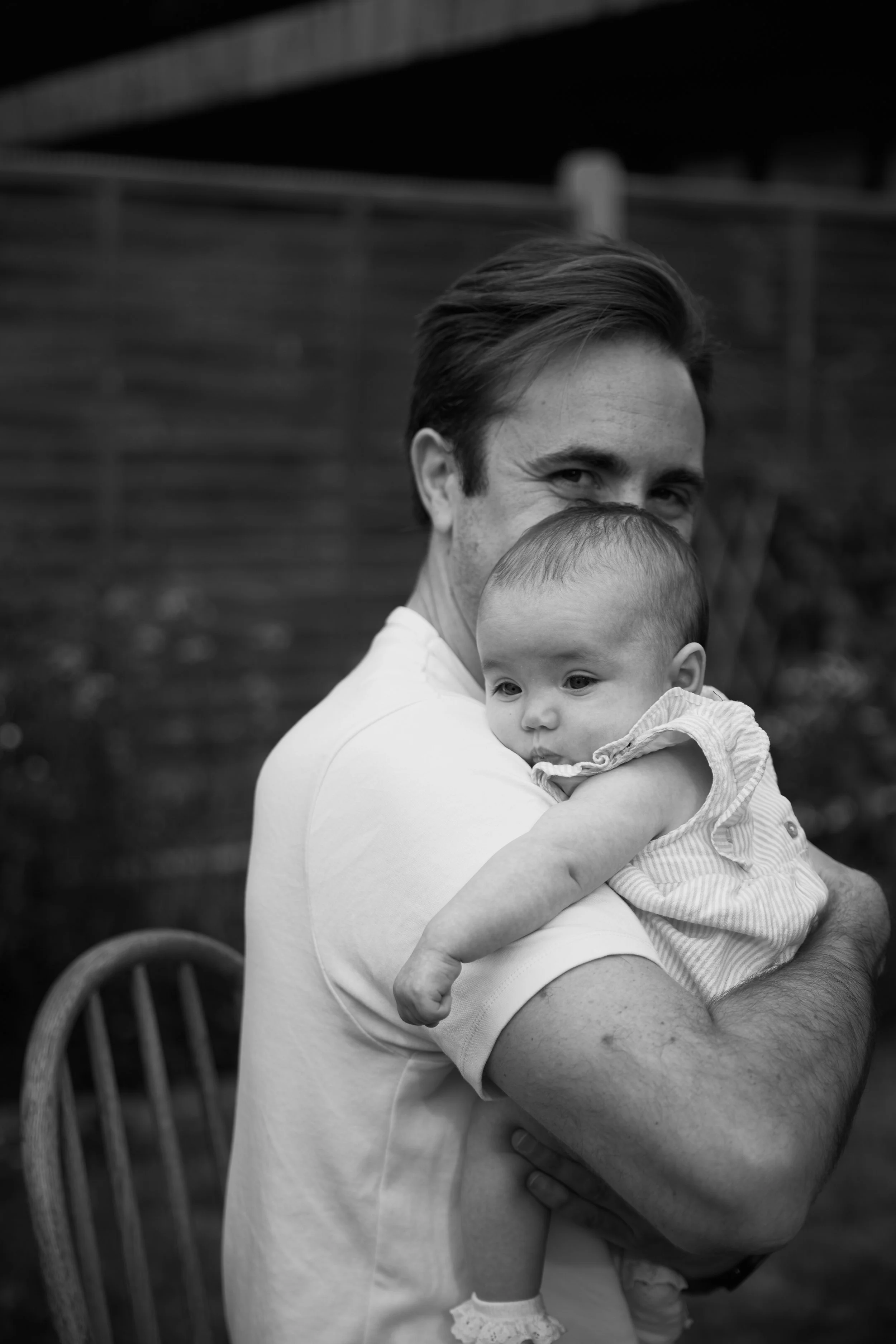 A man holding a young child outdoors, black and white photograph.