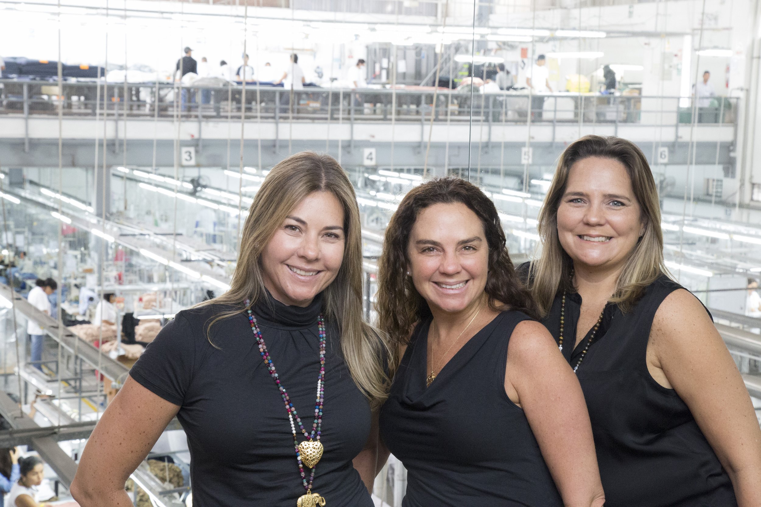 Three women smiling in a textile factory.