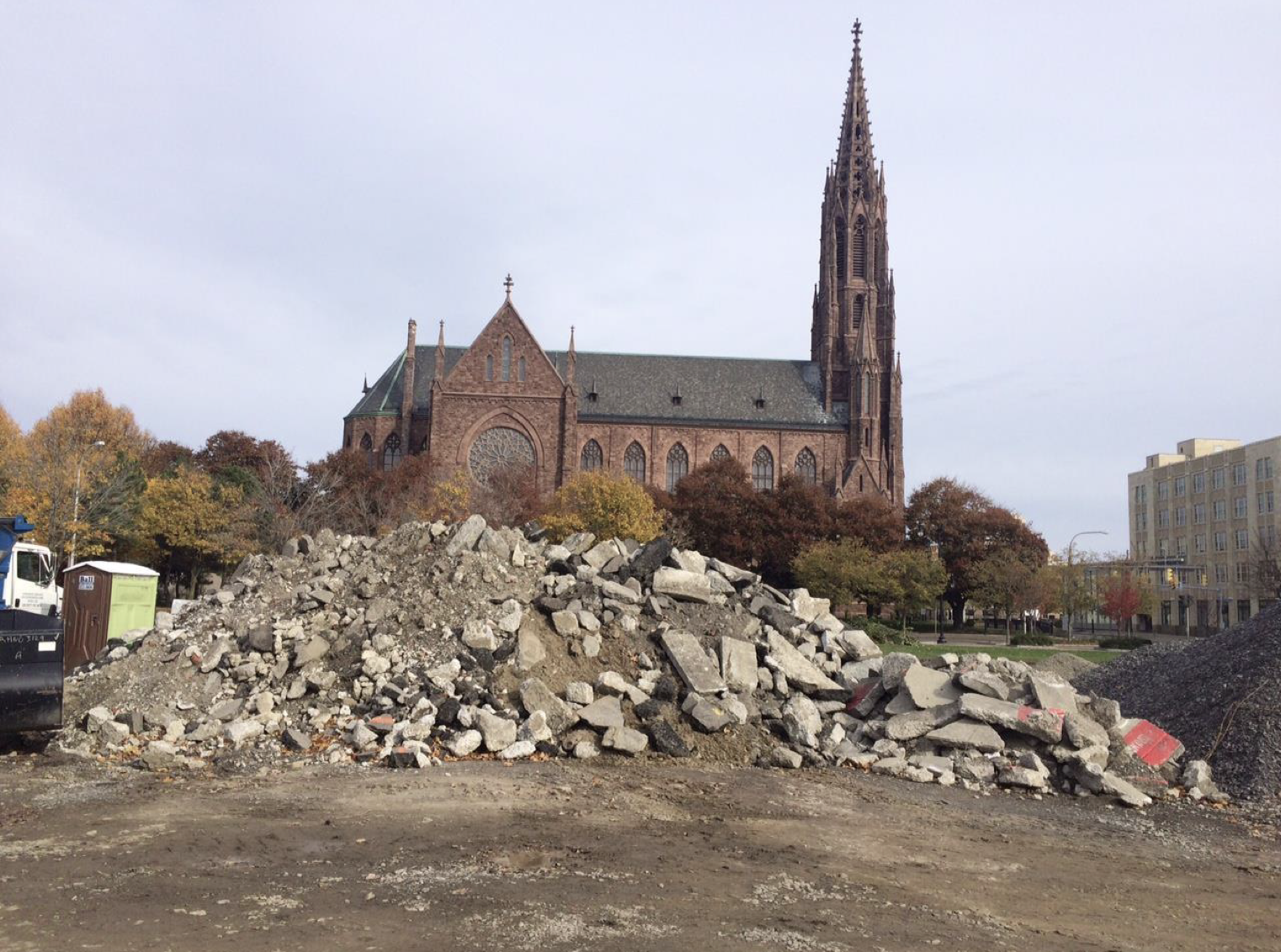   Site of the former Teck Theatre, Buffalo, New York.  The site was temporarily used to store construction materials for work on adjacent buildings, with demolition rubble in the foreground and St. Louis Roman Catholic Church in the background. Photo