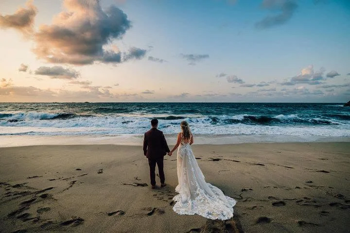 Couple holding hands on a beach looking out to sea
