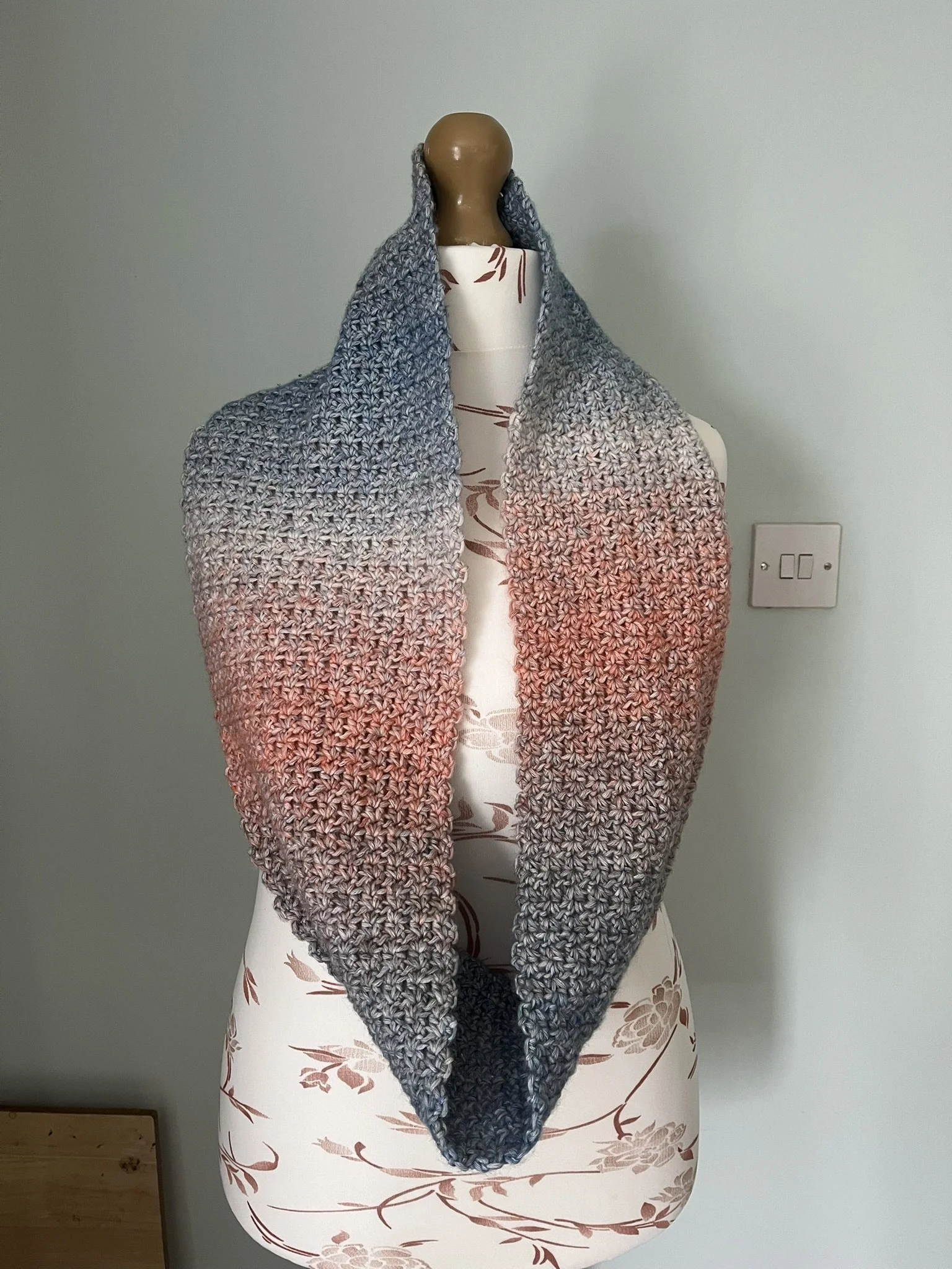 Handmade crochet infinity scarf in blue and coral colours wrapped around a mannequin