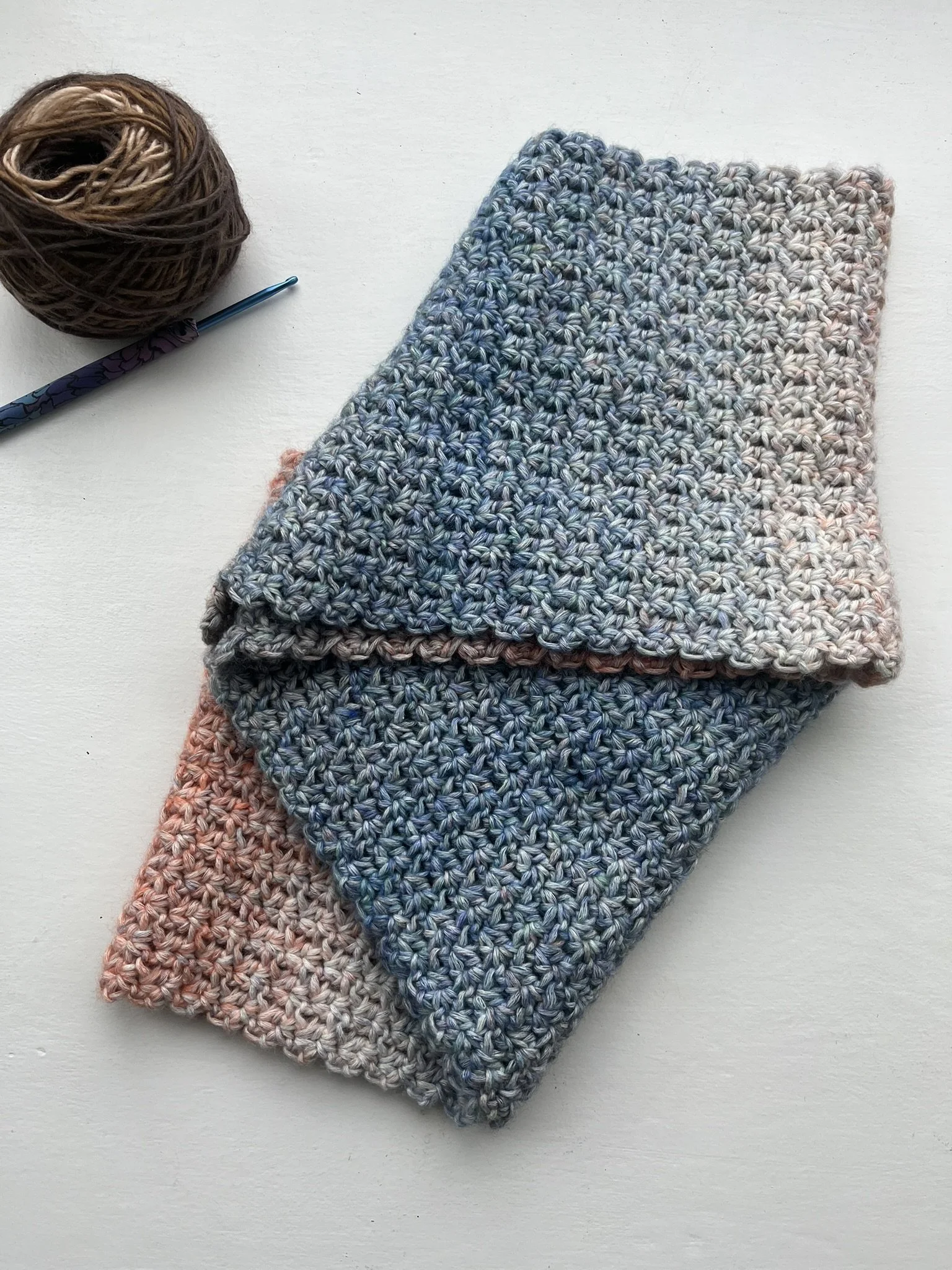 Handmade crochet infinity scarf in blue and coral colours displayed on a white background