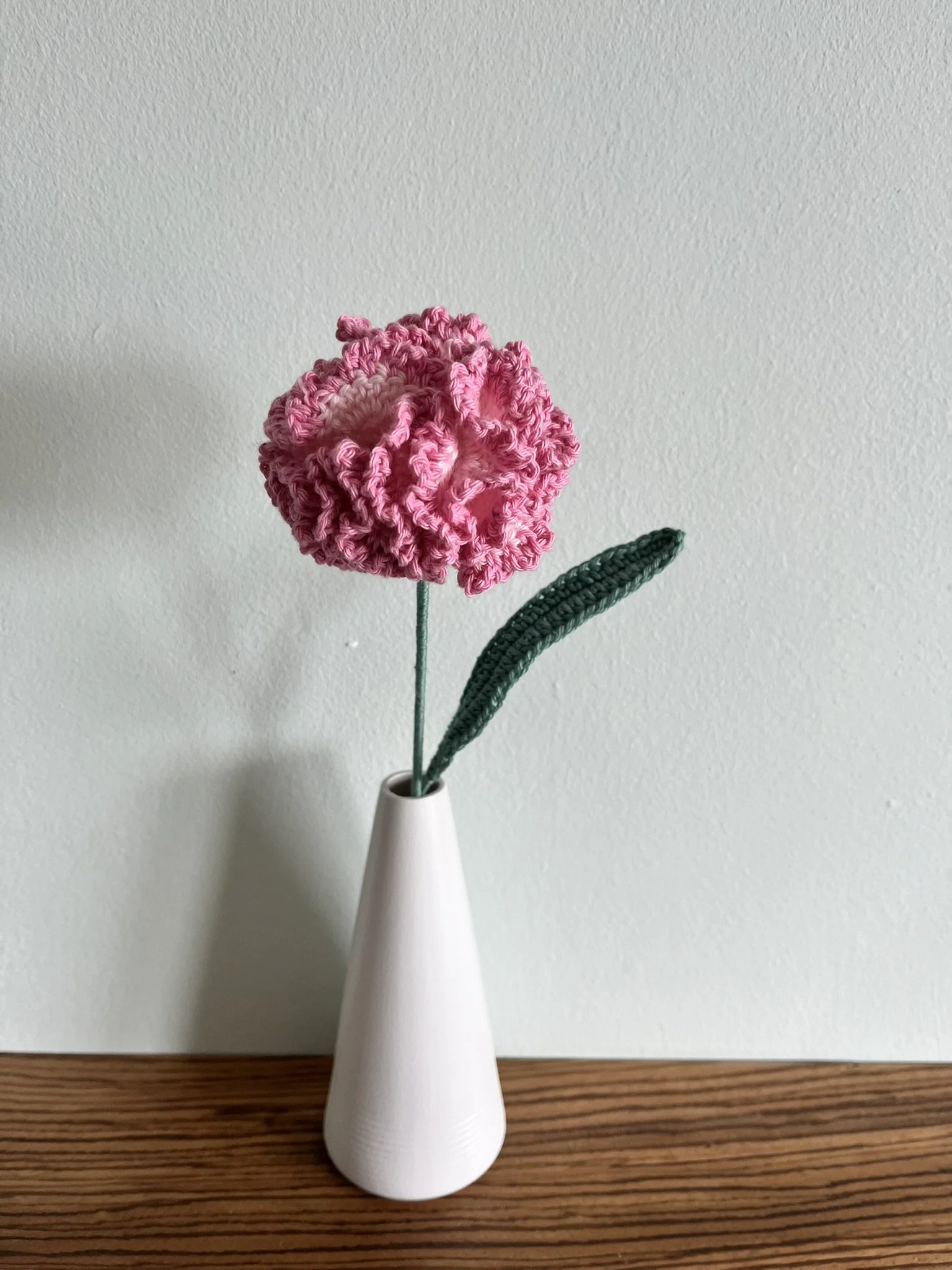 close-up of hand-crocheted carnation flower showing intricate crochet stitching and naturally frilly petals