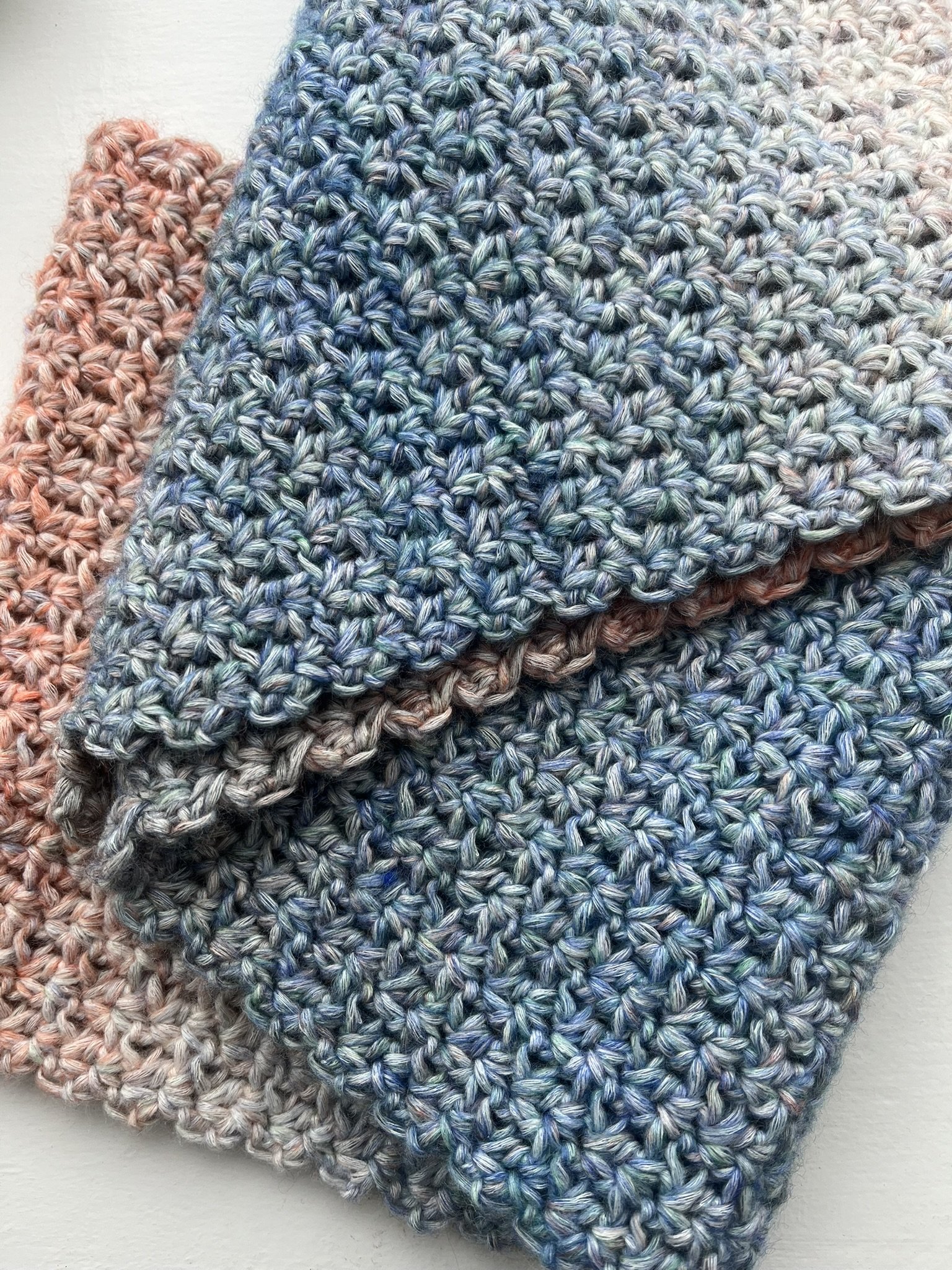 Handmade crochet infinity scarf in blue and coral colours displayed on a white background