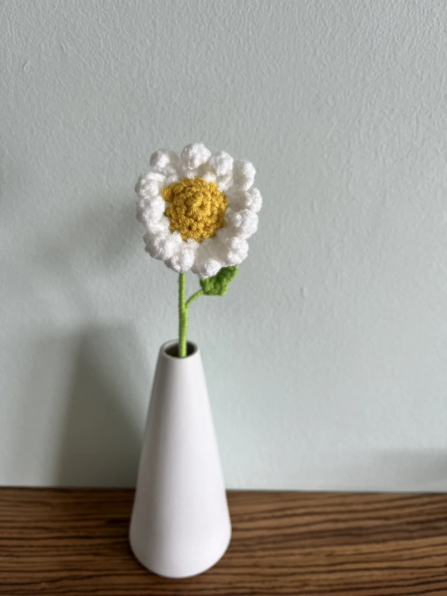 Close-up of hand-crocheted daisy flowers showing yellow centres and white petals with natural handmade variations