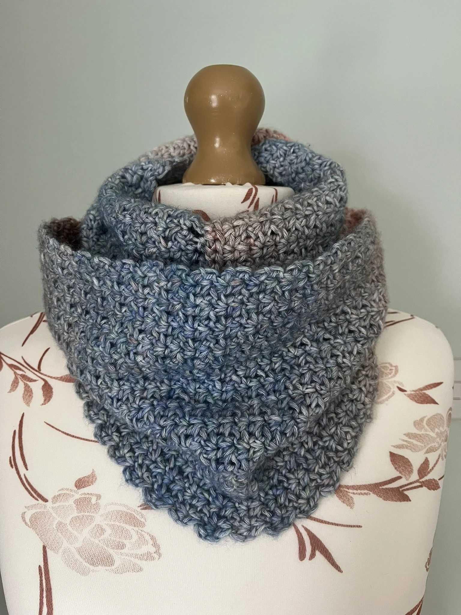Handmade crochet infinity scarf in blue and coral colours wrapped around a mannequin