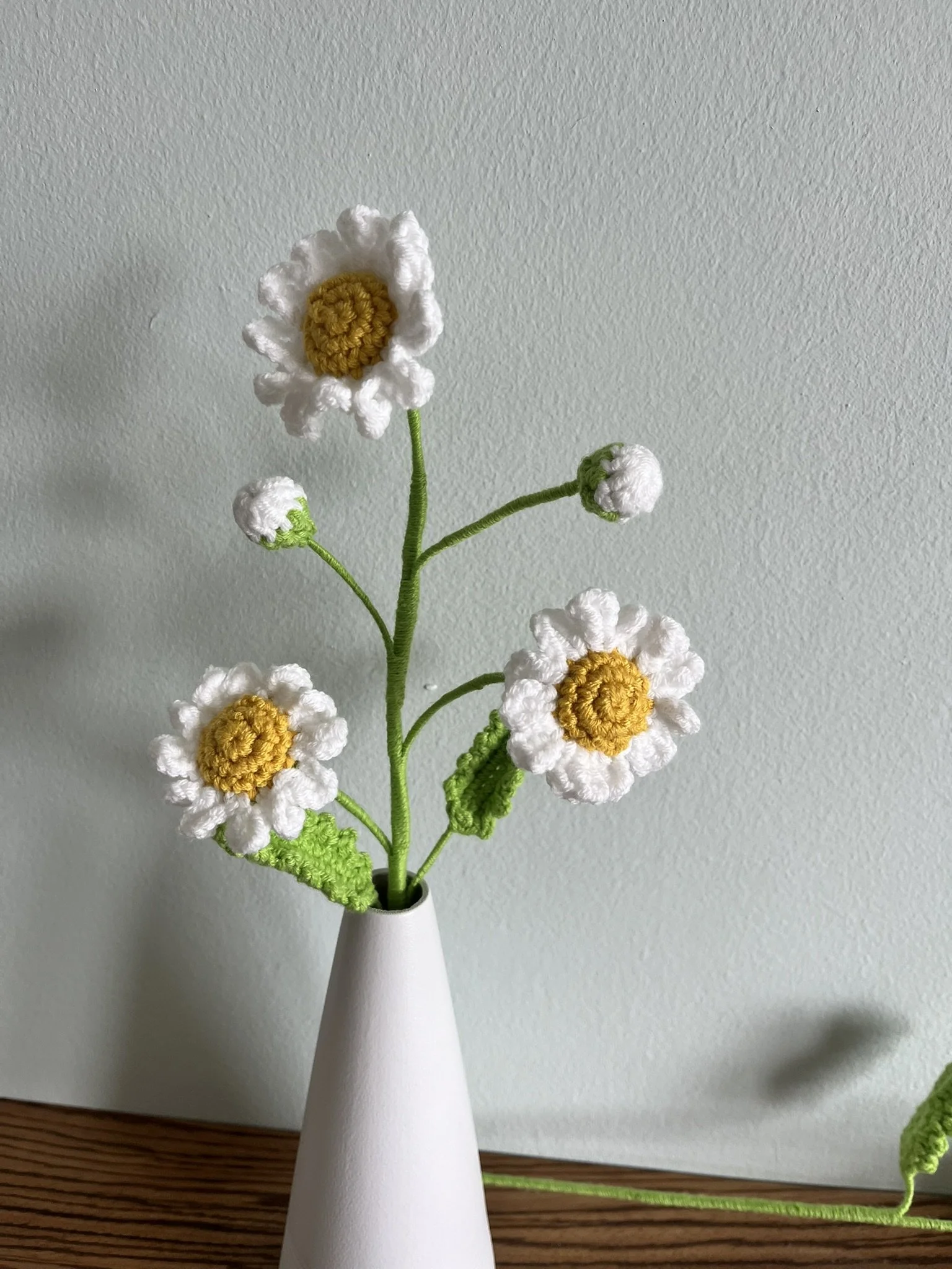 Close-up of hand-crocheted daisy flowers showing yellow centres and white petals with natural handmade variations