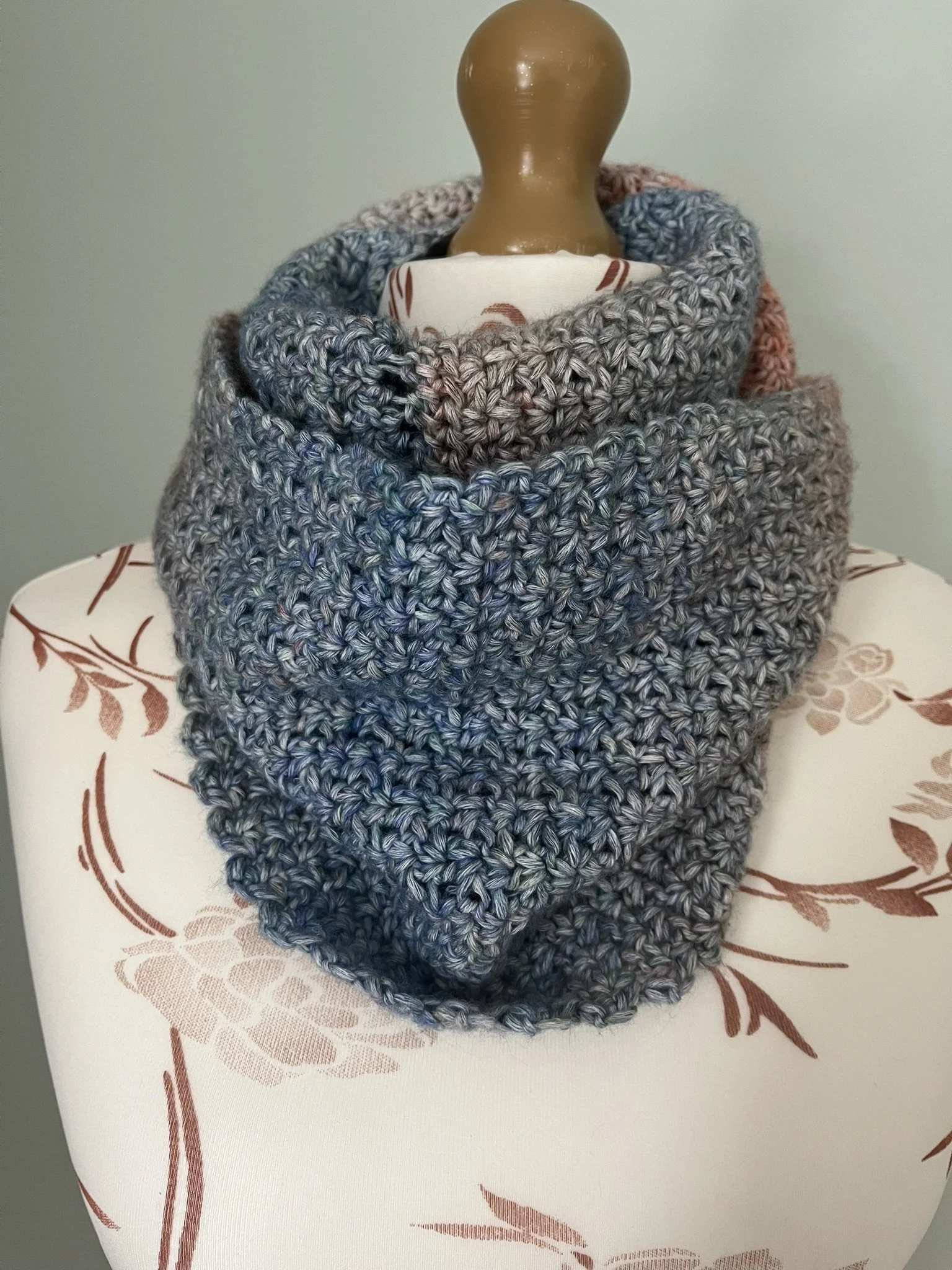 Handmade crochet infinity scarf in blue and coral colours wrapped around a mannequin