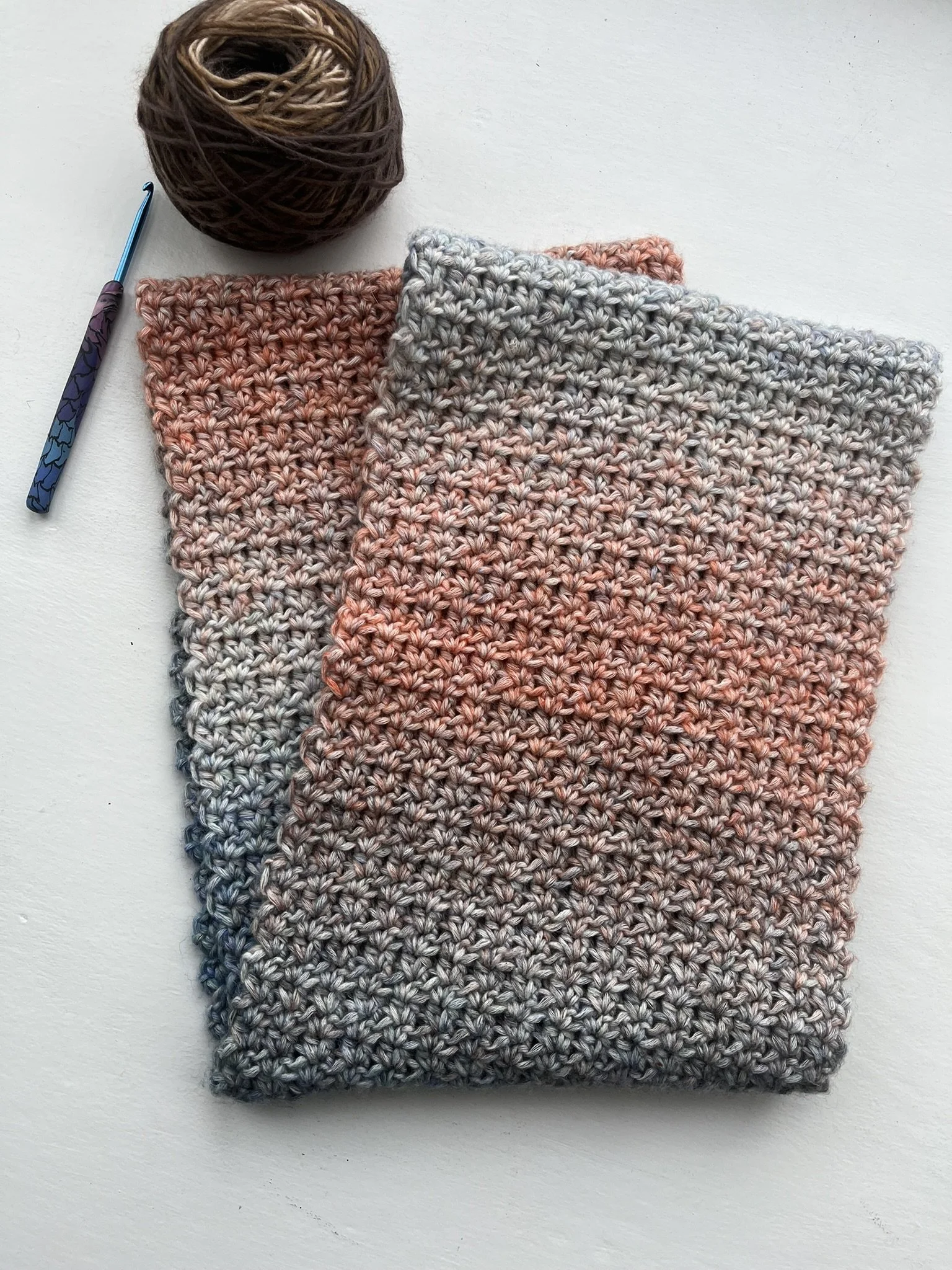 Handmade crochet infinity scarf in blue and coral colours displayed on a white background