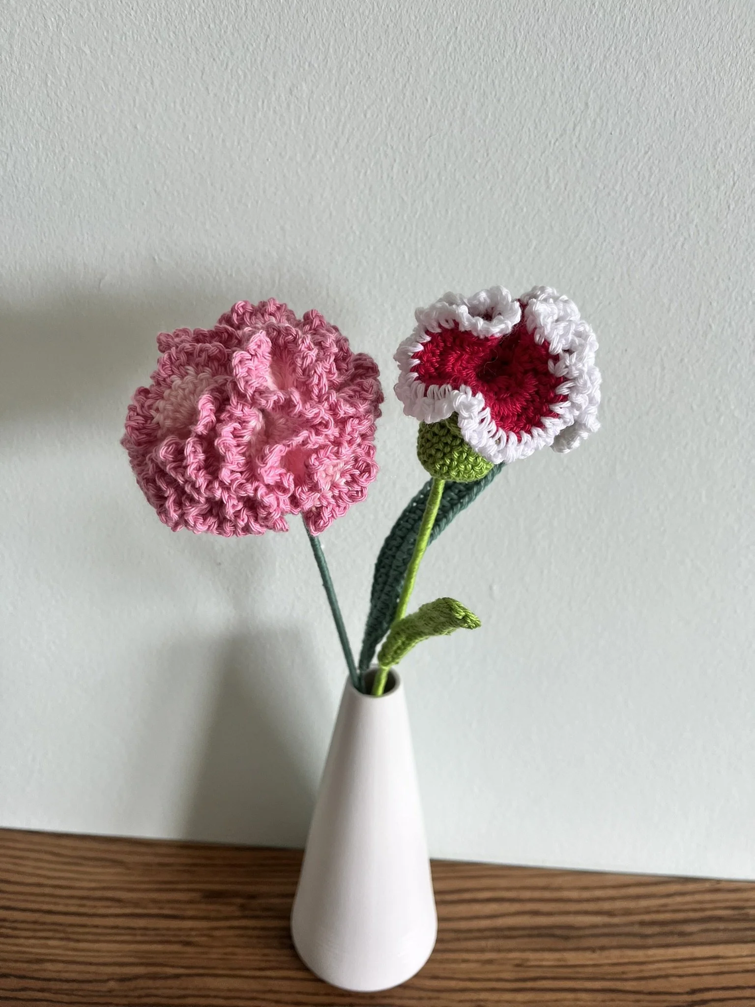 close-up of hand-crocheted carnation flower showing intricate crochet stitching and naturally frilly petals