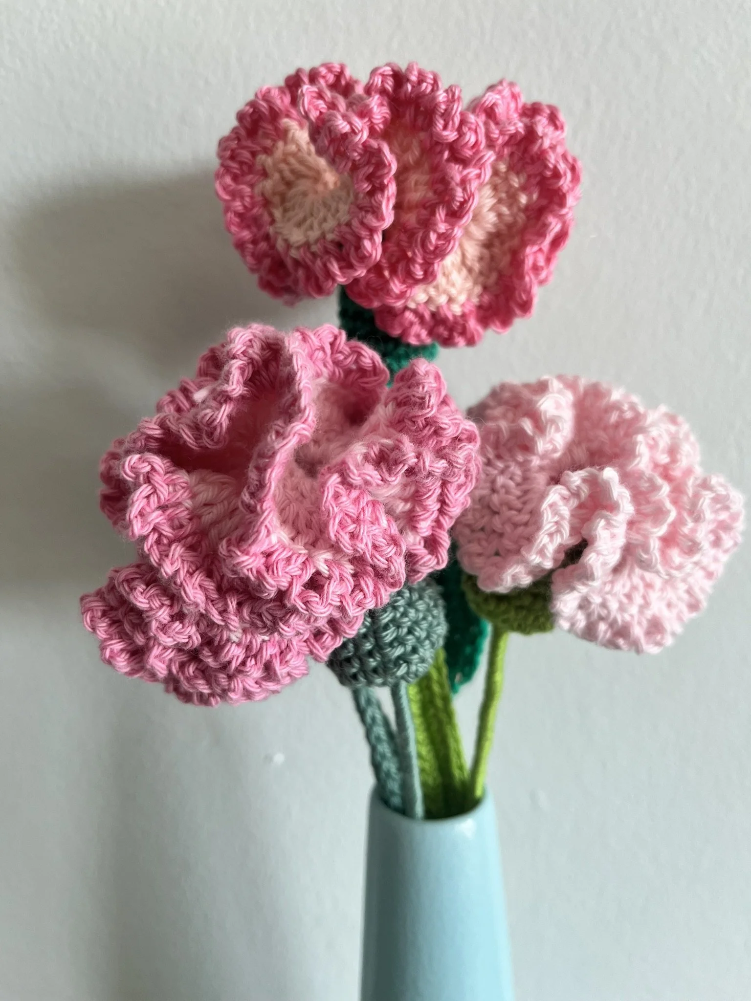 close-up of hand-crocheted carnation flower showing intricate crochet stitching and naturally frilly petals