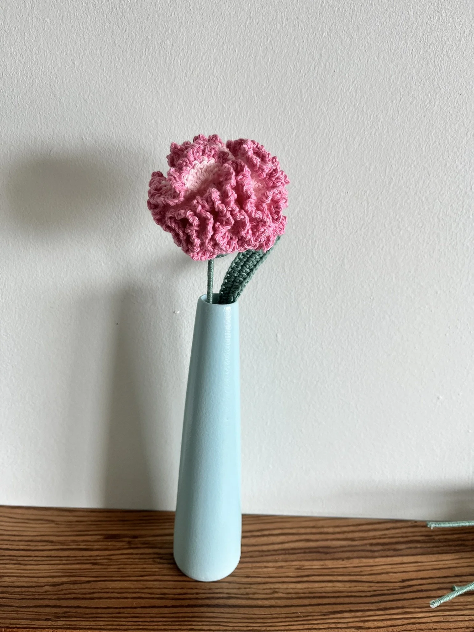 close-up of hand-crocheted carnation flower showing intricate crochet stitching and naturally frilly petals