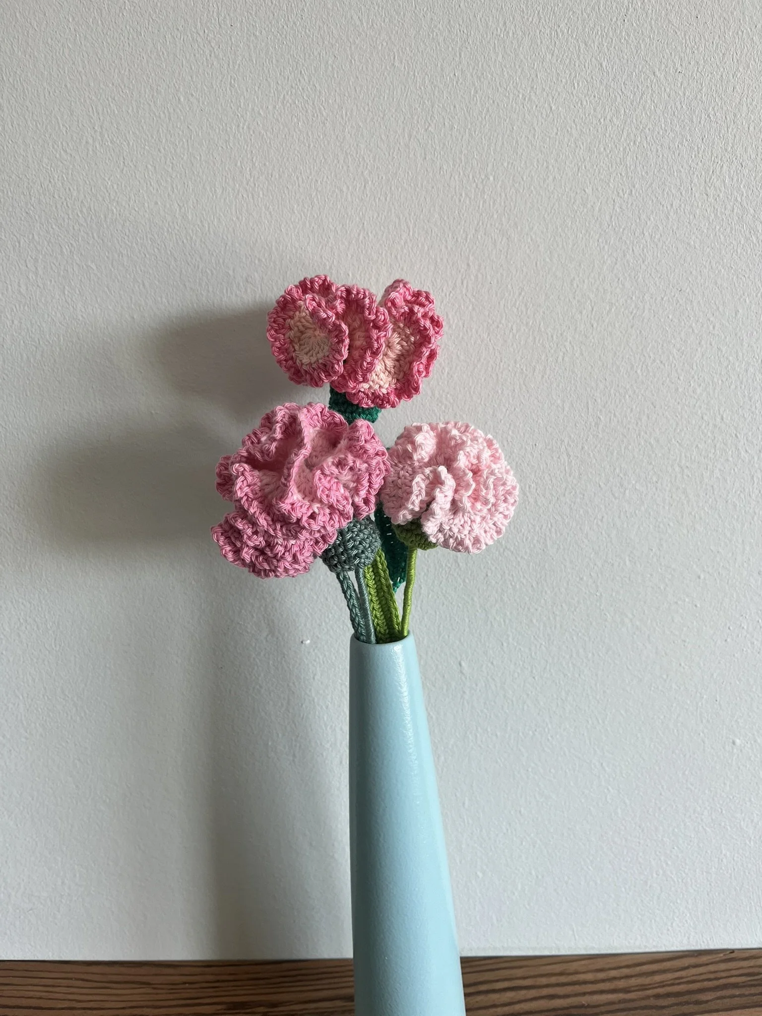 close-up of hand-crocheted carnation flower showing intricate crochet stitching and naturally frilly petals