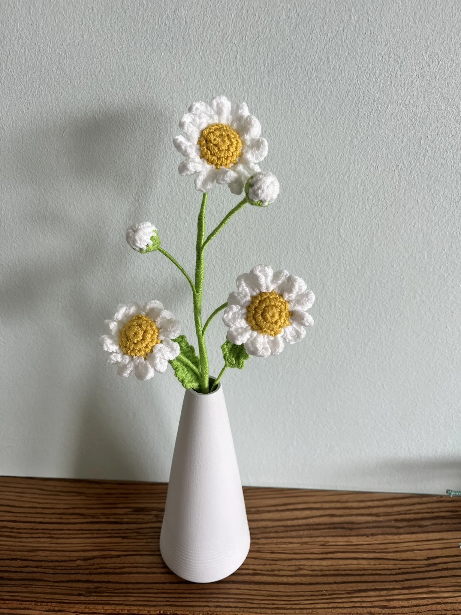 Close-up of hand-crocheted daisy flowers showing yellow centres and white petals with natural handmade variations