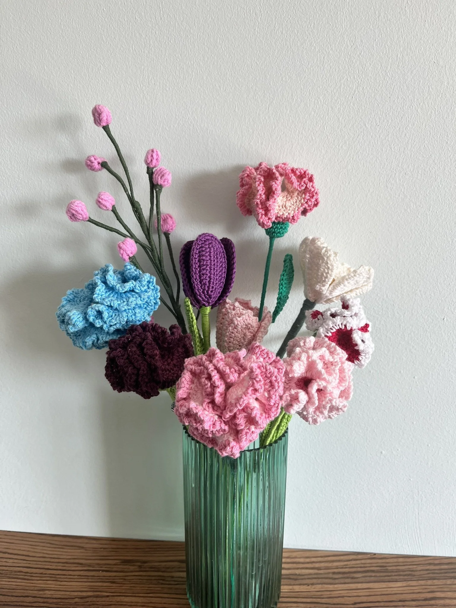 A hand-crocheted arrangement of carnations, tulips and cosmos arranged in a clear vase